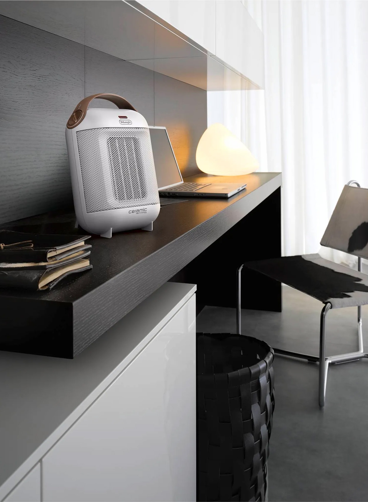 Scena biurowa z białym grzejnikiem ceramicznym, laptopem i czarnym biurkiem. Scena jest nowoczesna.