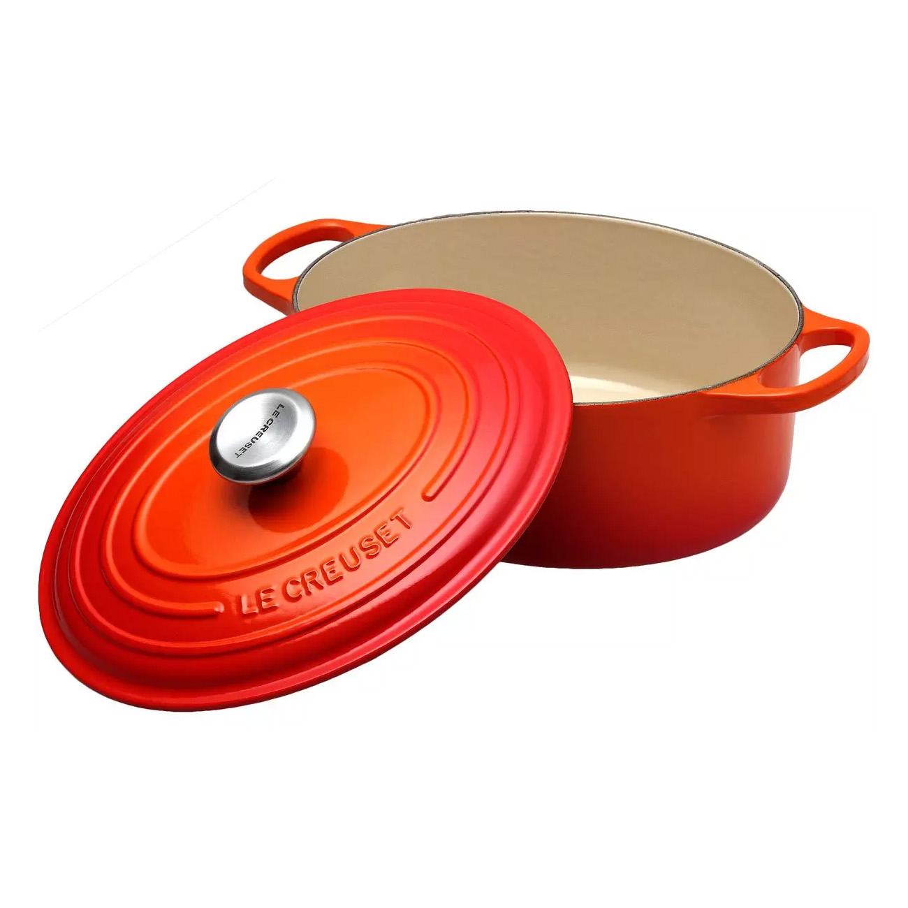 Czerwony garnek Le Creuset z pokrywką. Pokrywka jest z boku. Białe tło.