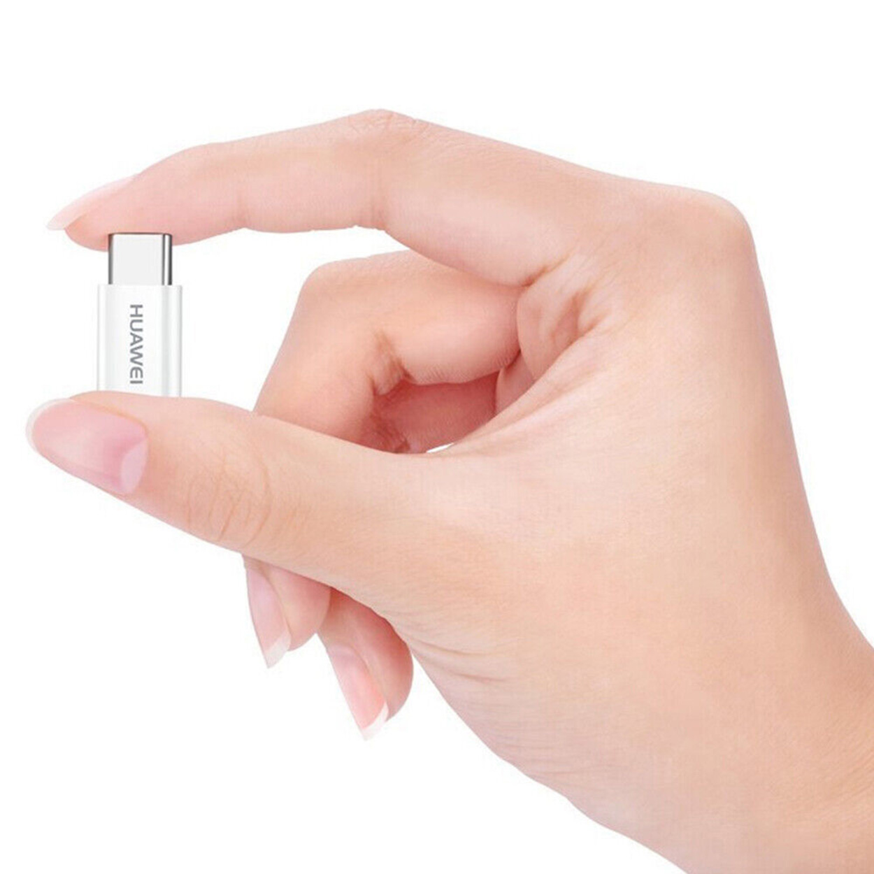 Una mano sostiene un adaptador USB-C Huawei blanco. El nombre de la marca es visible.