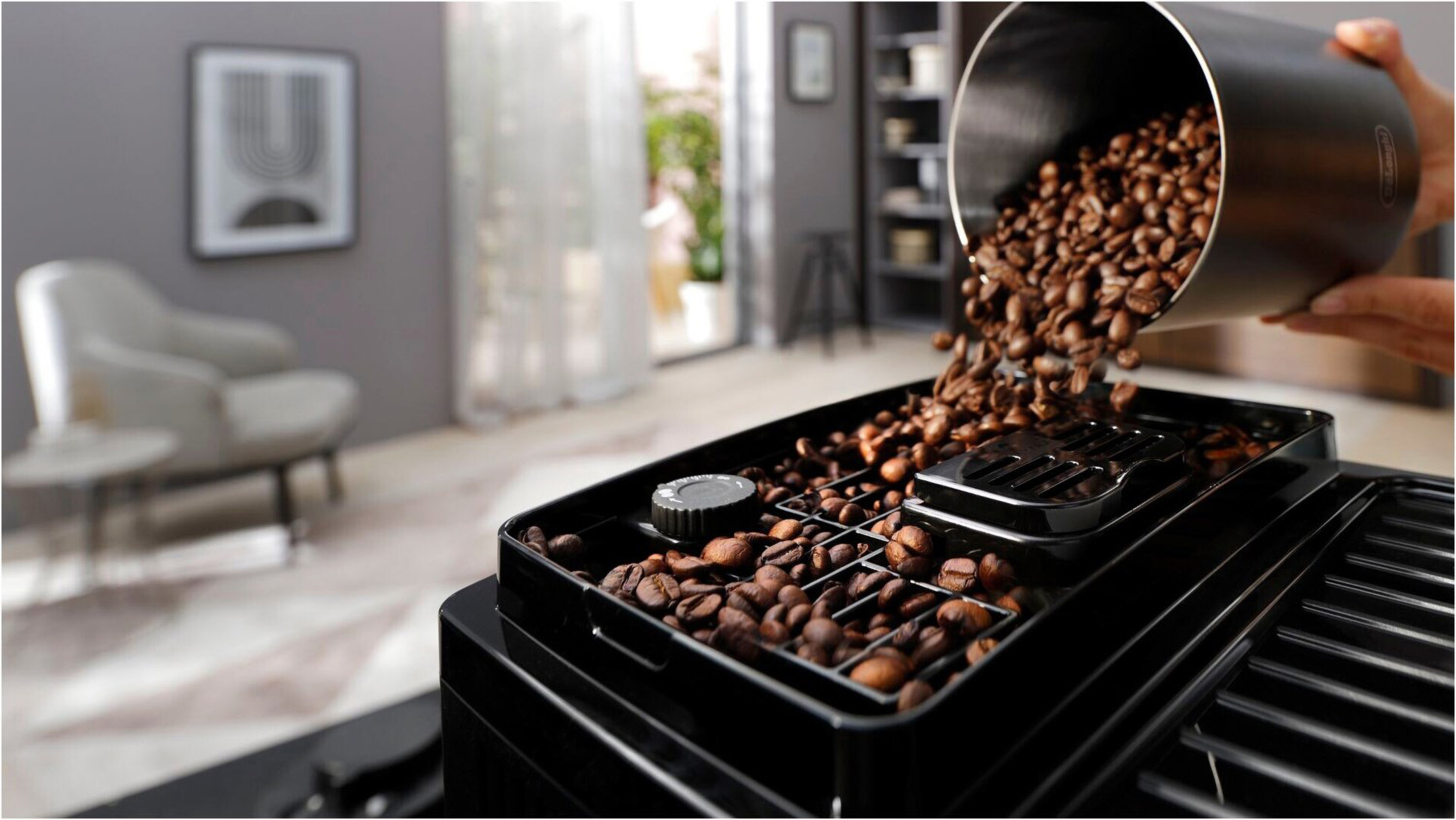 Ziarna kawy są wlewane do czarnego górnego pojemnika ekspresu do kawy, w pomieszczeniu.