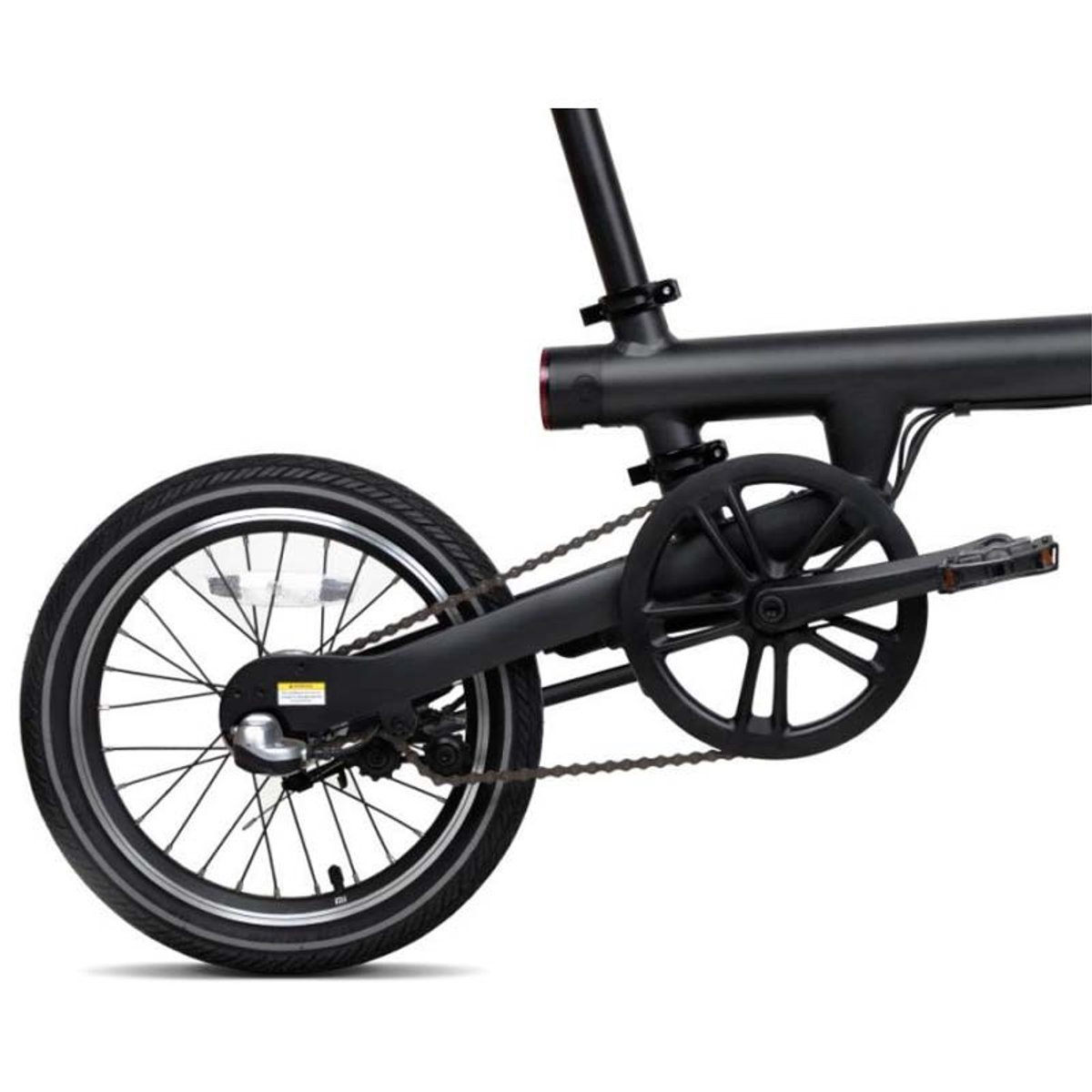 Bicicletta nera con catena e ingranaggi visibili. La ruota posteriore è prominente. Sfondo bianco.