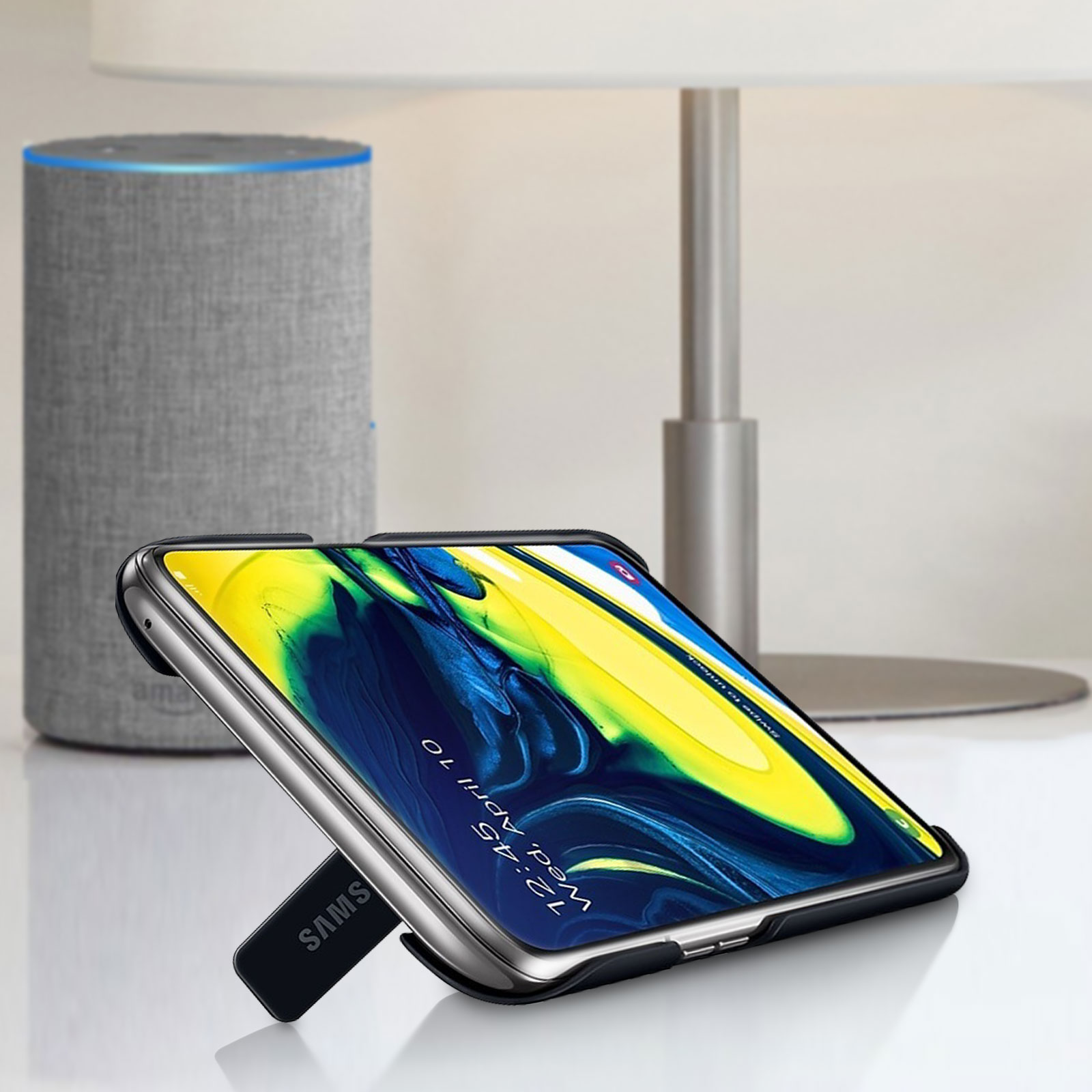 Smartphone in una custodia, appoggiato, con un altoparlante e una lampada sullo sfondo.