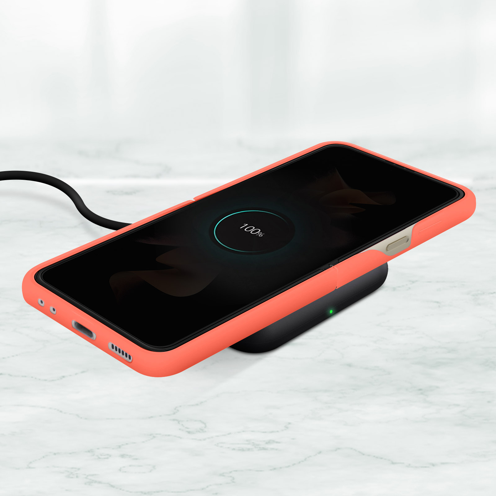 Orangefarbenes Telefon auf einem kabellosen Ladegerät, zeigt 100% geladen an. Schwarzes Ladegerät, weiße Marmoroberfläche.