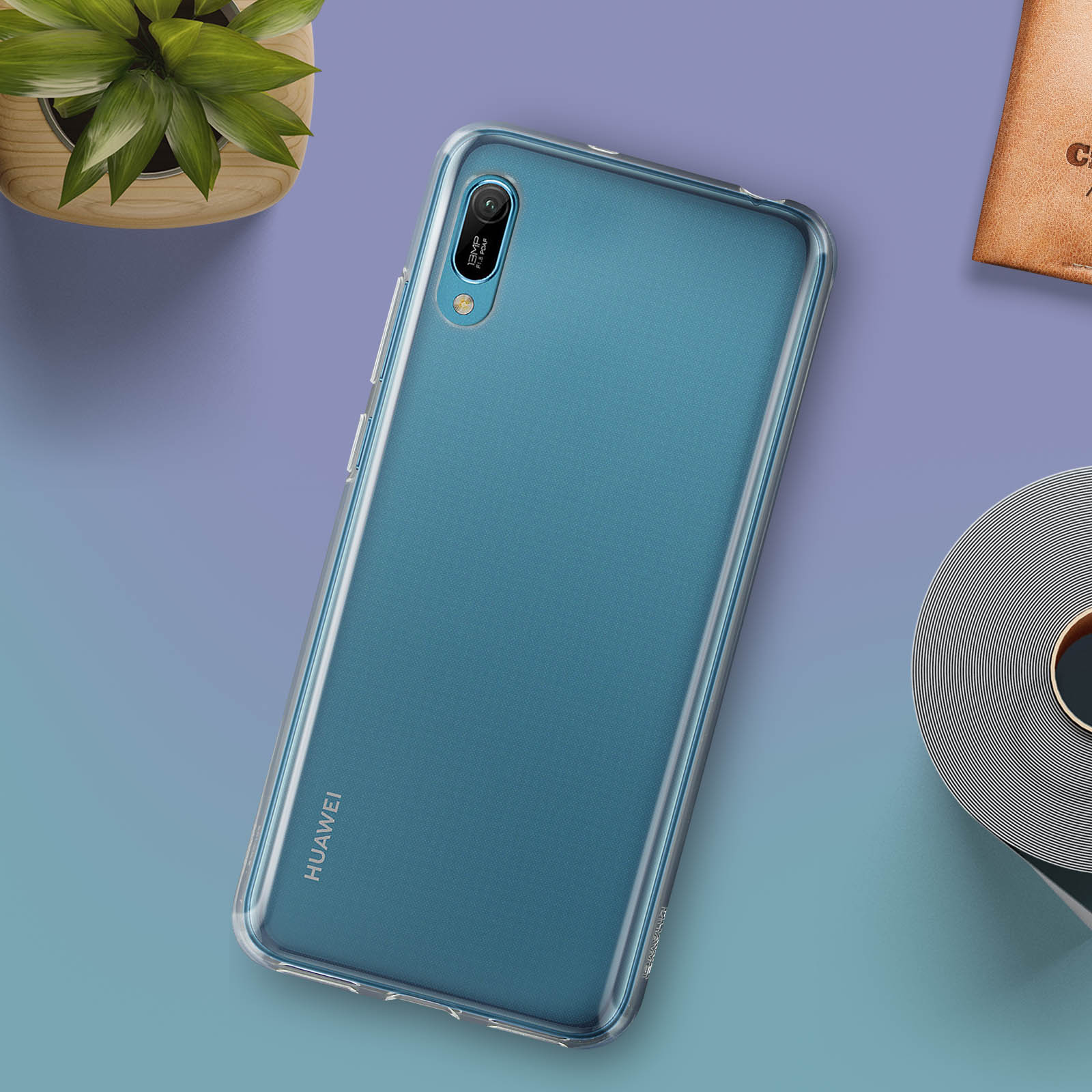 Smartfon w niebieskim etui na fioletowej powierzchni z rośliną i notatnikiem.