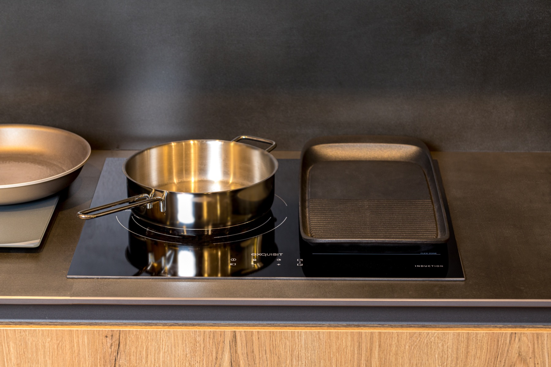 Una placa de cocina negra con dos sartenes encima. Una es una sartén y la otra una sartén para asar.
