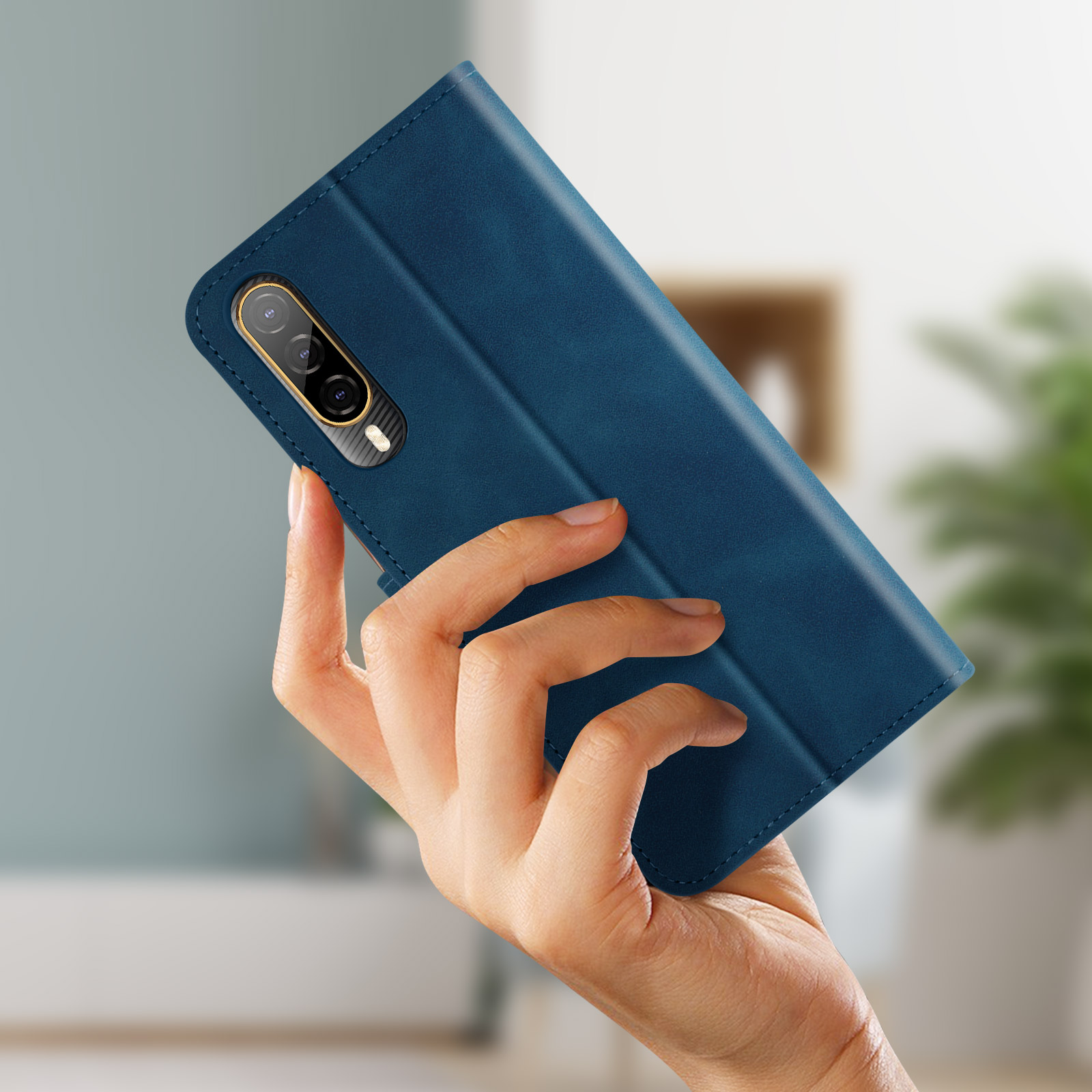 Mano che tiene custodia blu per telefono con sporgenza fotocamera, chiusa, su sfondo verde sfocato.