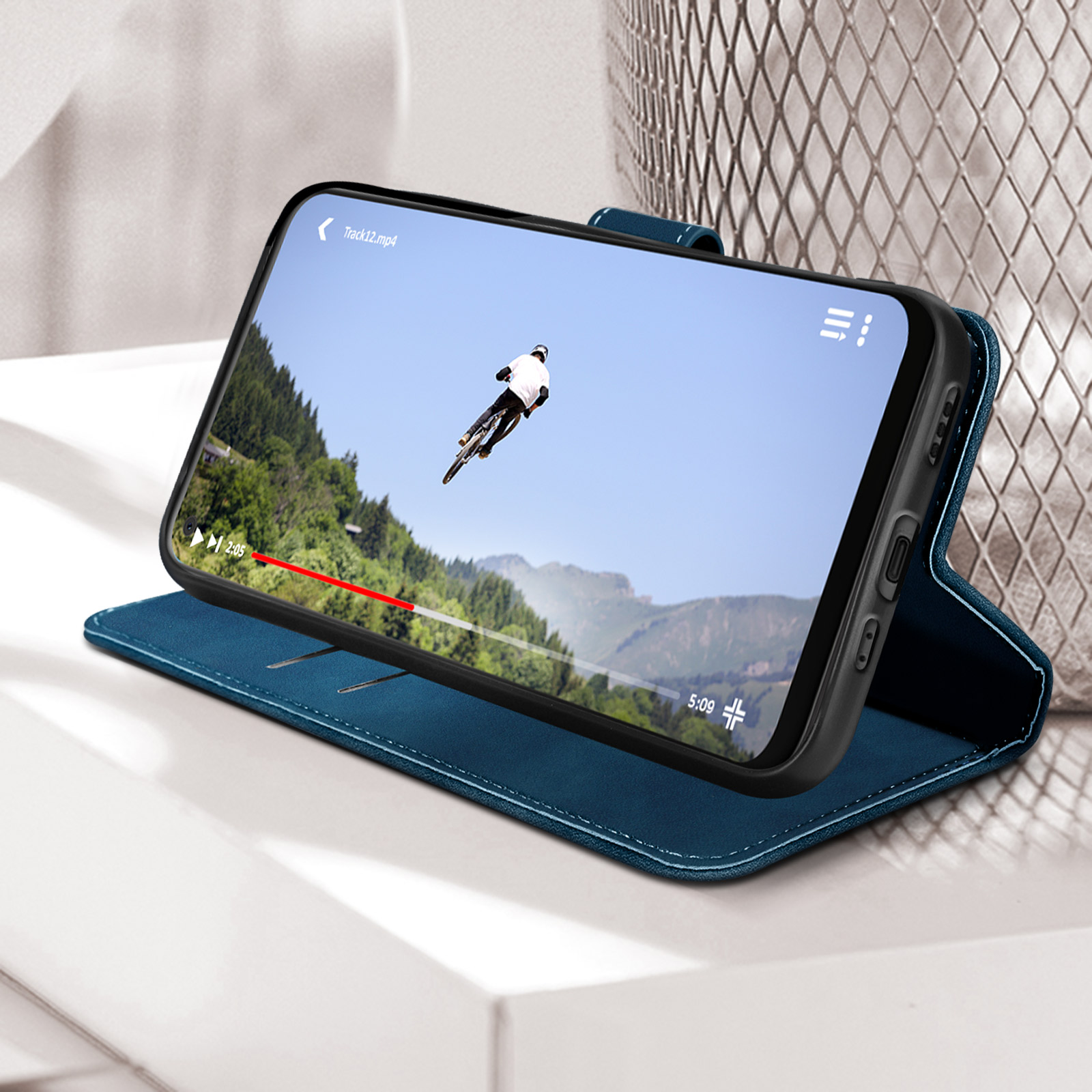 Telefono in una custodia blu riproduce un video di un ciclista su una strada di montagna.