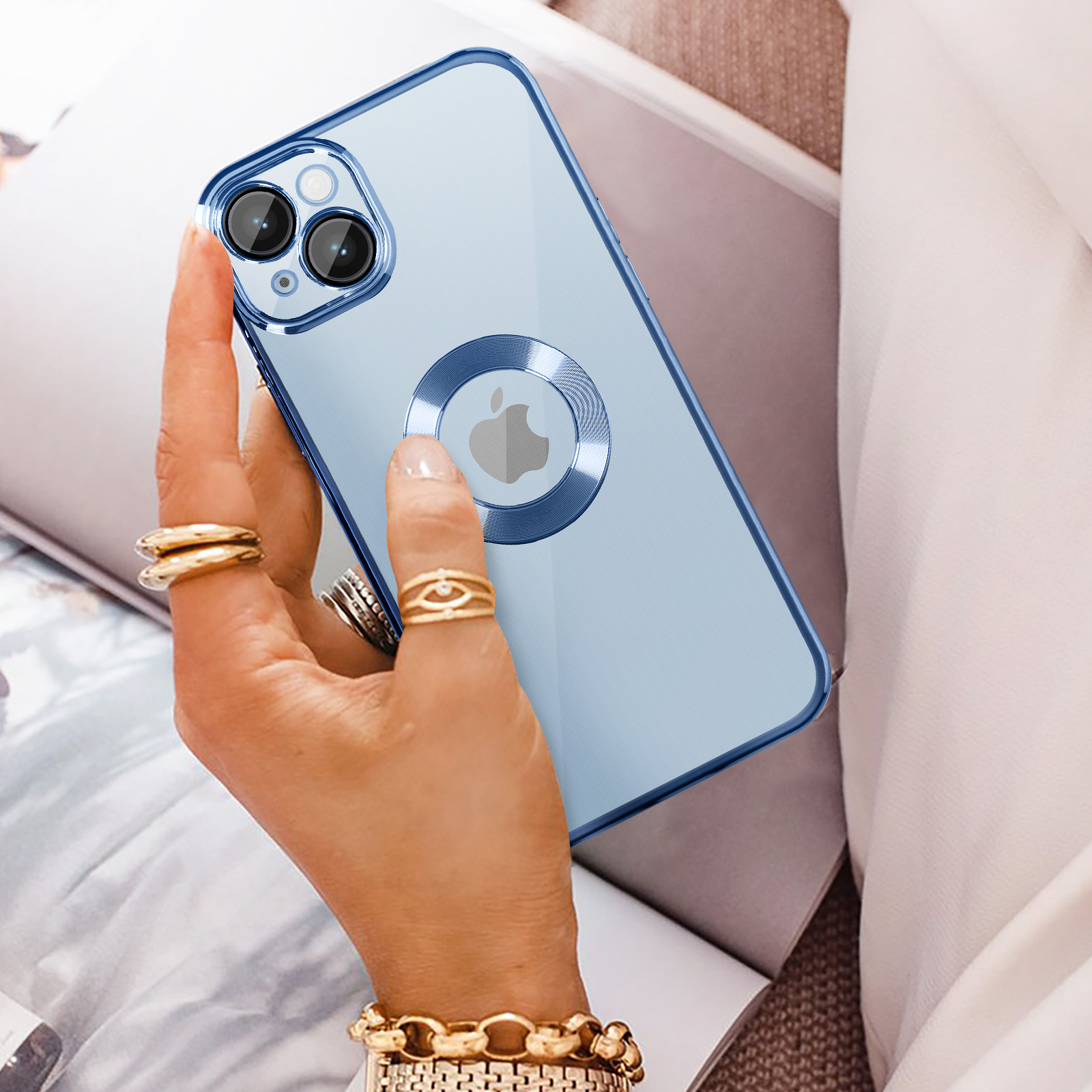 Mano che tiene iPhone blu con custodia trasparente e anelli d'oro.