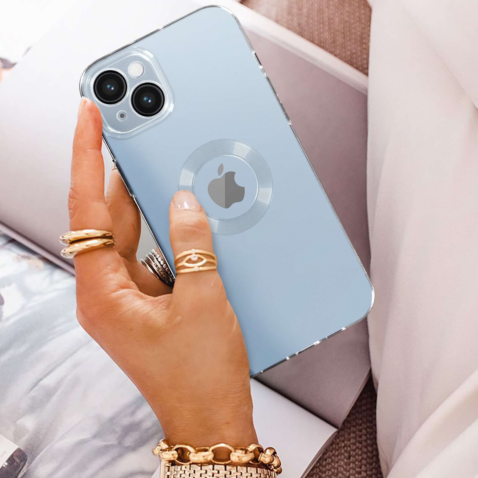 Una mano che tiene un telefono con una custodia trasparente, che mostra il logo Apple. Lo sfondo è morbido e sfocato.