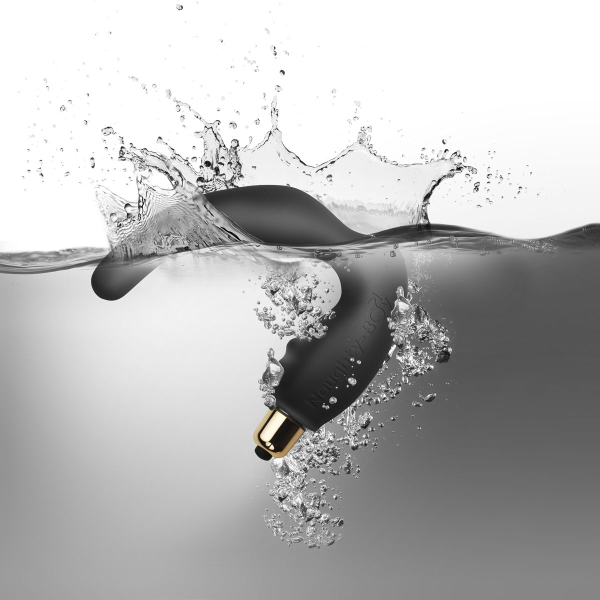 Giocattolo sessuale nero in acqua. Schizzi, bolle. Punta e base dorate. Testo Naughty Boy. Sfondo bianco.