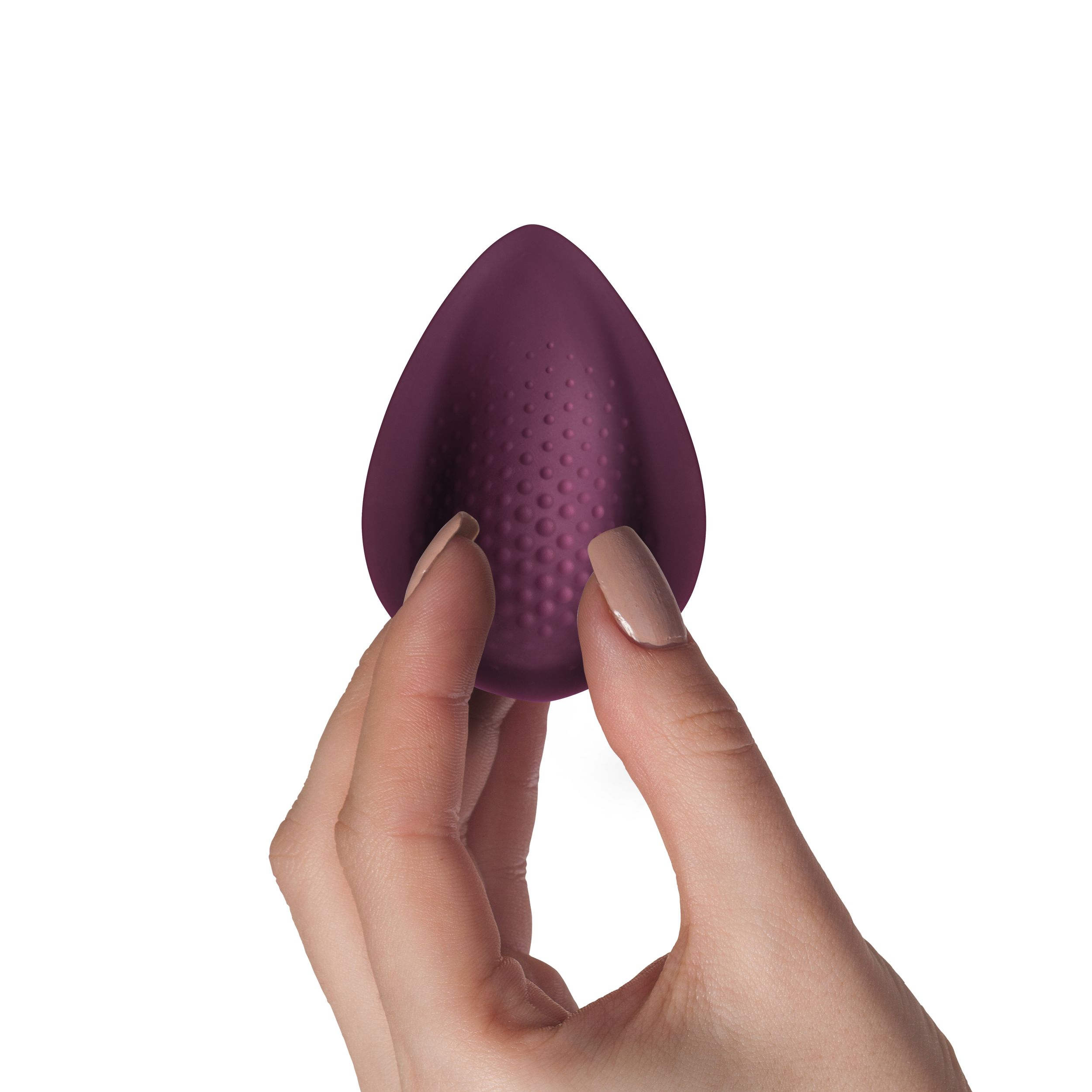 Eine Hand hält ein dunkelviolettes Sexspielzeug mit strukturierter Oberfläche, vor weißem Hintergrund.