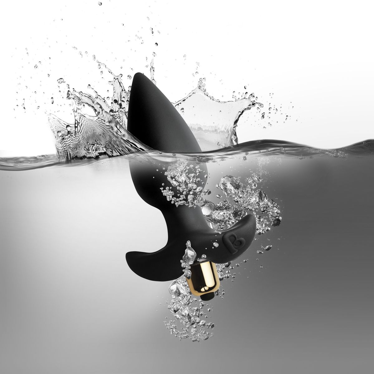 Ein schwarzes Sexspielzeug, das in Wasser getaucht ist und Spritzer verursacht. Es hat eine goldfarbene Basis und ist von Blasen umgeben.