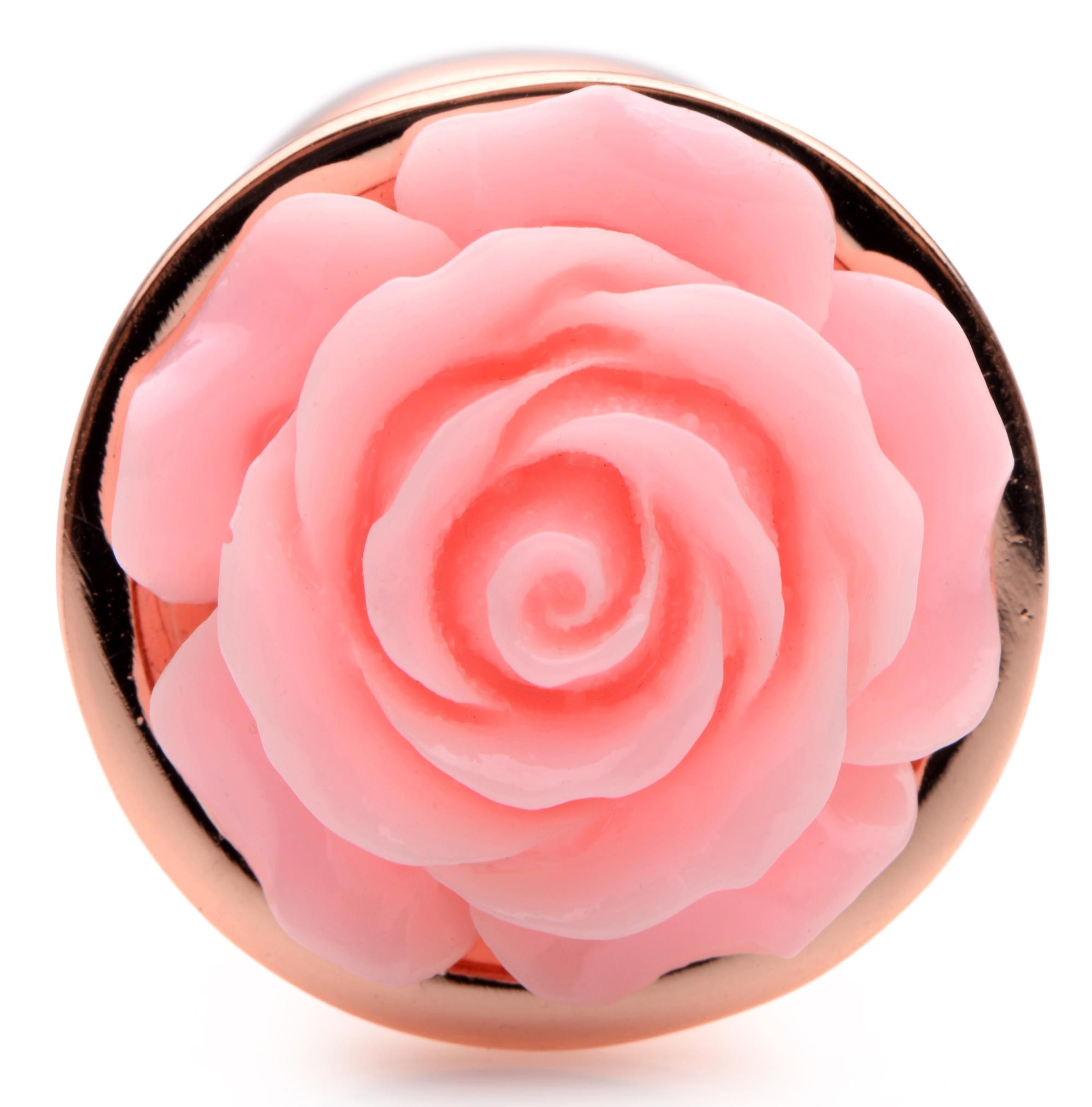 Nahaufnahme einer rosa Rose in goldfarbener Fassung, vor weißem Hintergrund.