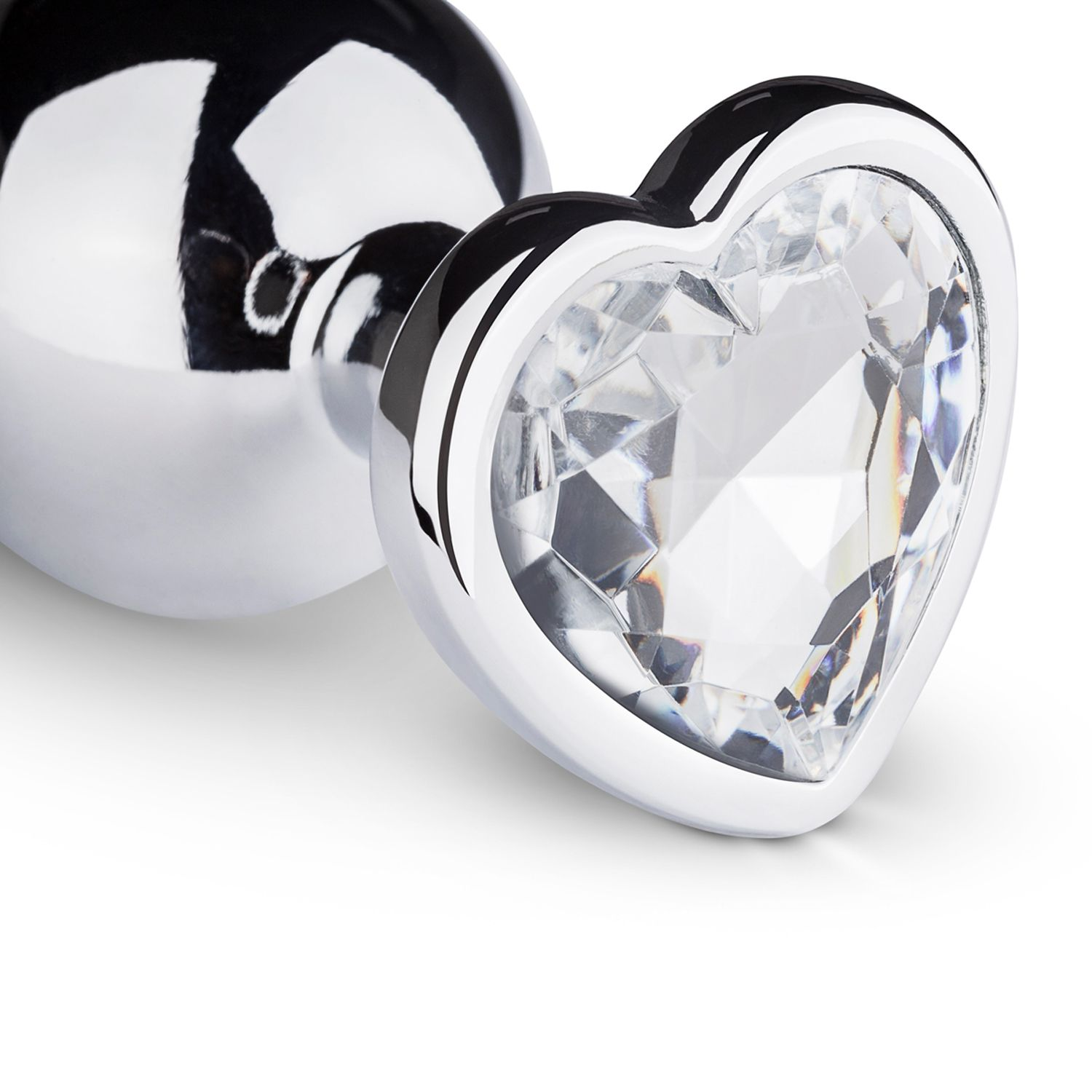 Un tapón anal brillante, de color plateado, con una joya transparente en forma de corazón en el extremo.