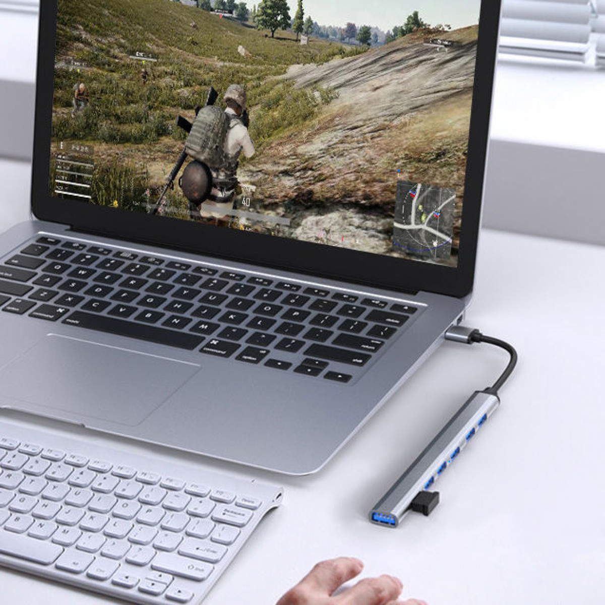 Laptop mit Spiel auf dem Bildschirm, Tastatur und angeschlossenem USB-Hub.
