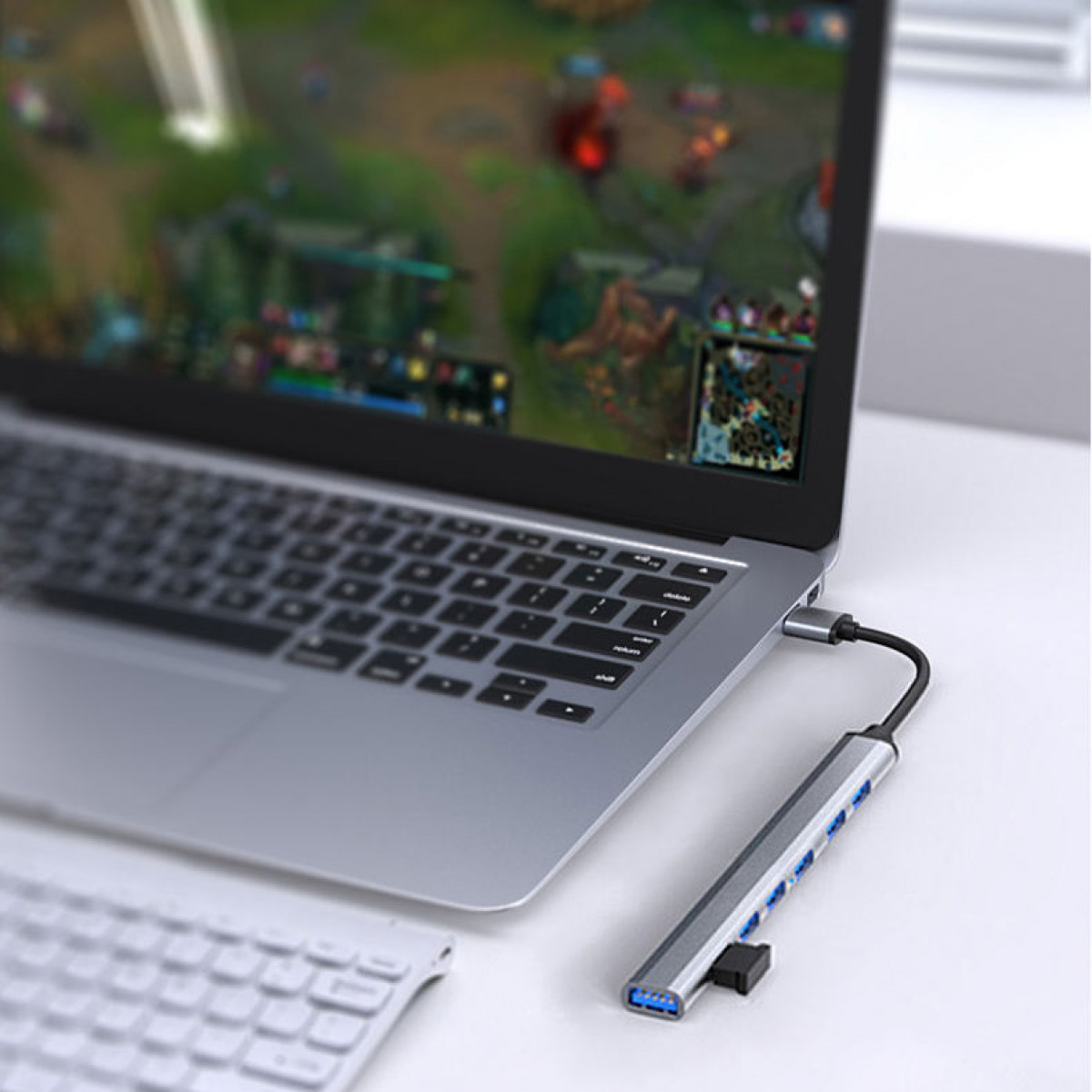 Ein Laptop mit angeschlossenem USB-Hub mit blauen Lichtern und weißer Oberfläche.
