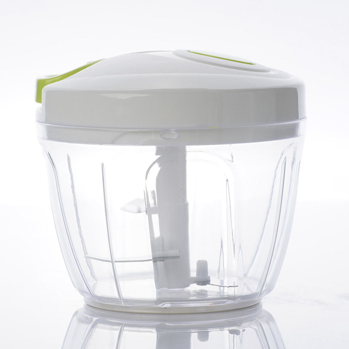 Un picador de alimentos blanco y verde. Reflejado en una superficie blanca. Fondo blanco.