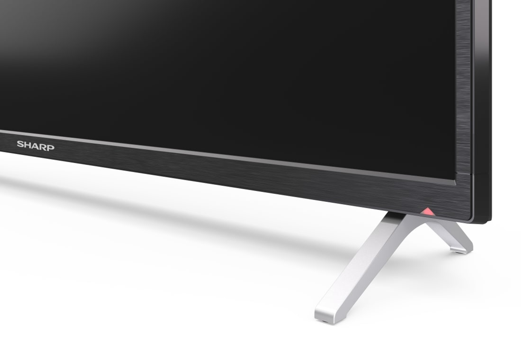 Primo piano della parte inferiore di un televisore Sharp. Mostra il supporto e una spia rossa.