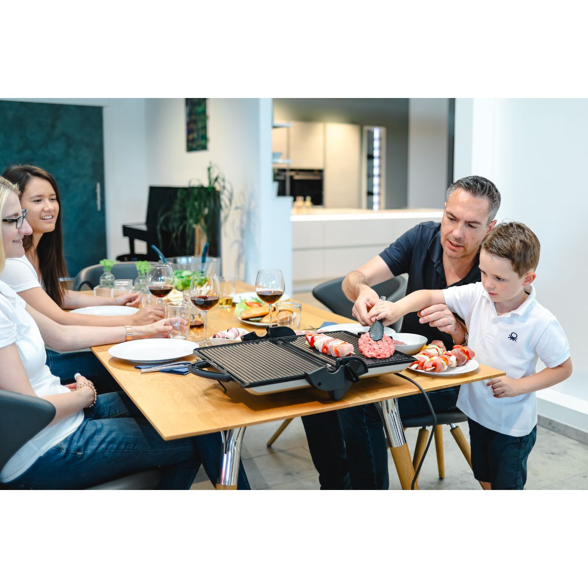 Familie grillt Essen auf einem Tisch mit einem Grill.