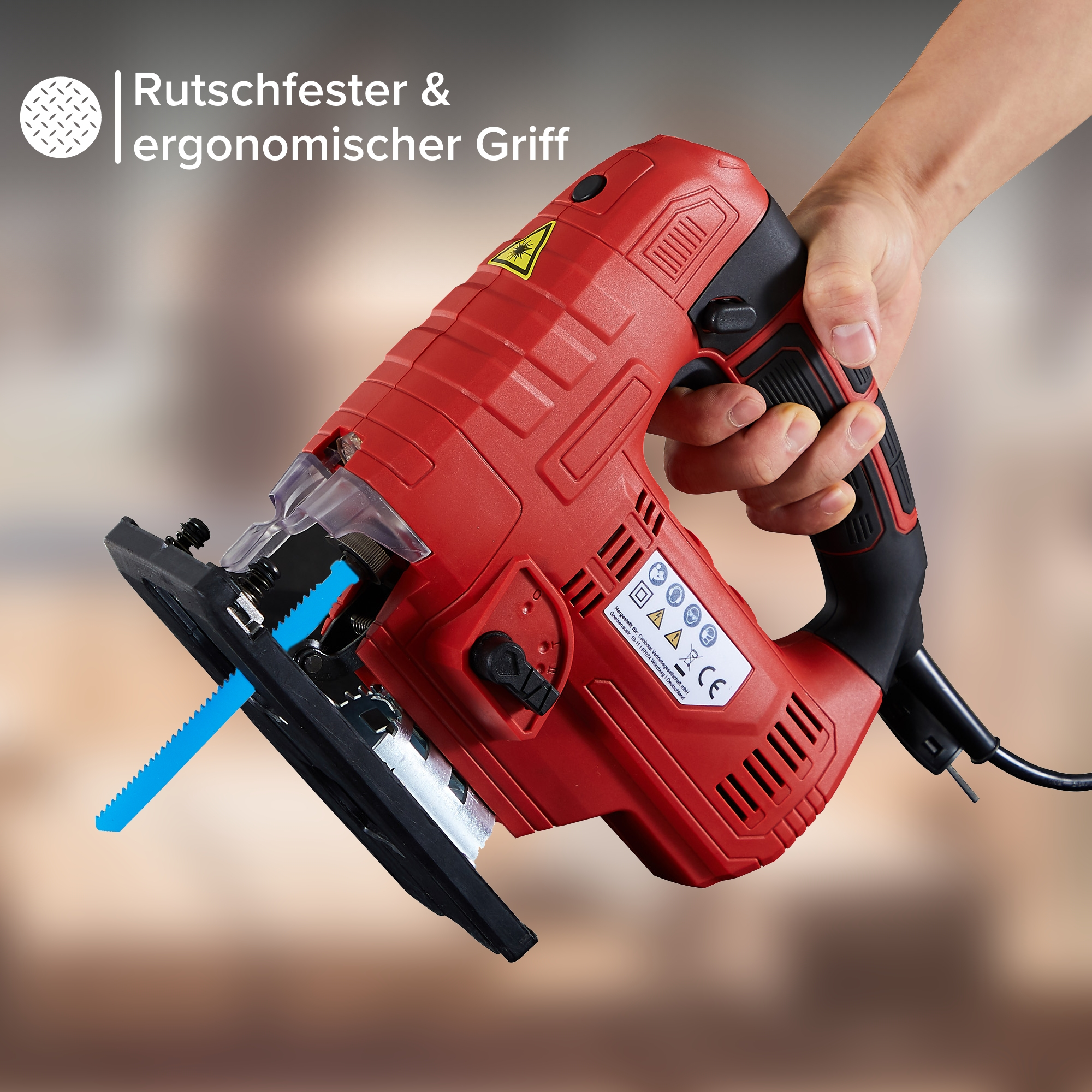 Eine rote Stichsäge, von einer Hand gehalten, mit blauem Sägeblatt, vor weißem Hintergrund.