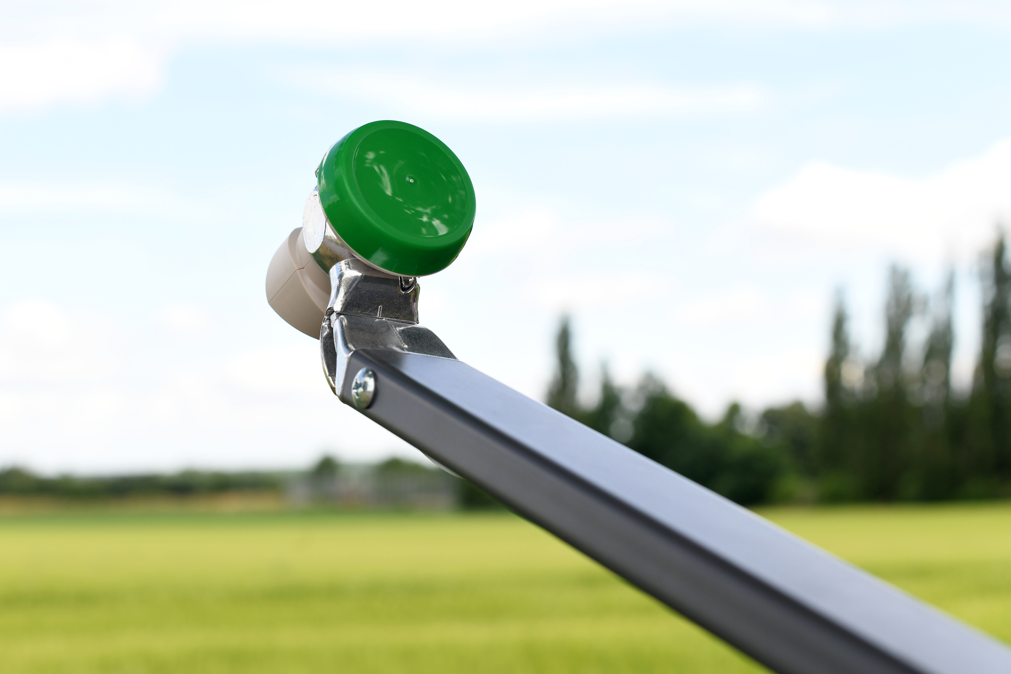 Eine Satellitenschüssel mit grüner Kappe, grauem Arm und grünem Feld im Hintergrund.