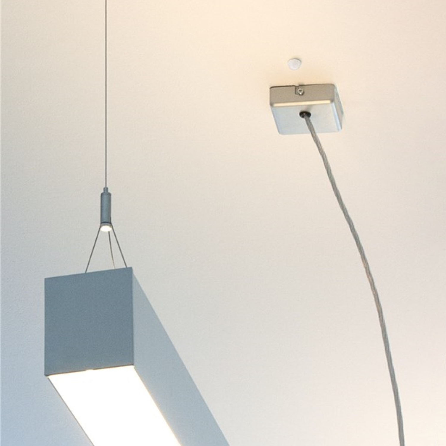 Moderne Deckenleuchte. Ein rechteckiges Licht hängt unter einer quadratischen Befestigung.