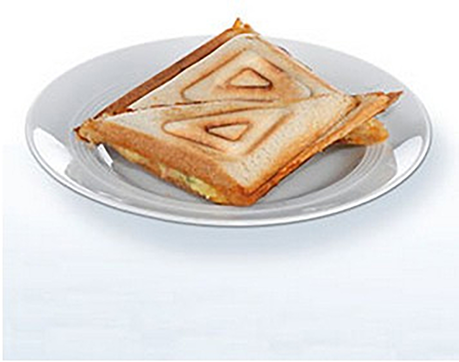 Dos mitades de un sándwich de queso a la plancha en un plato blanco.