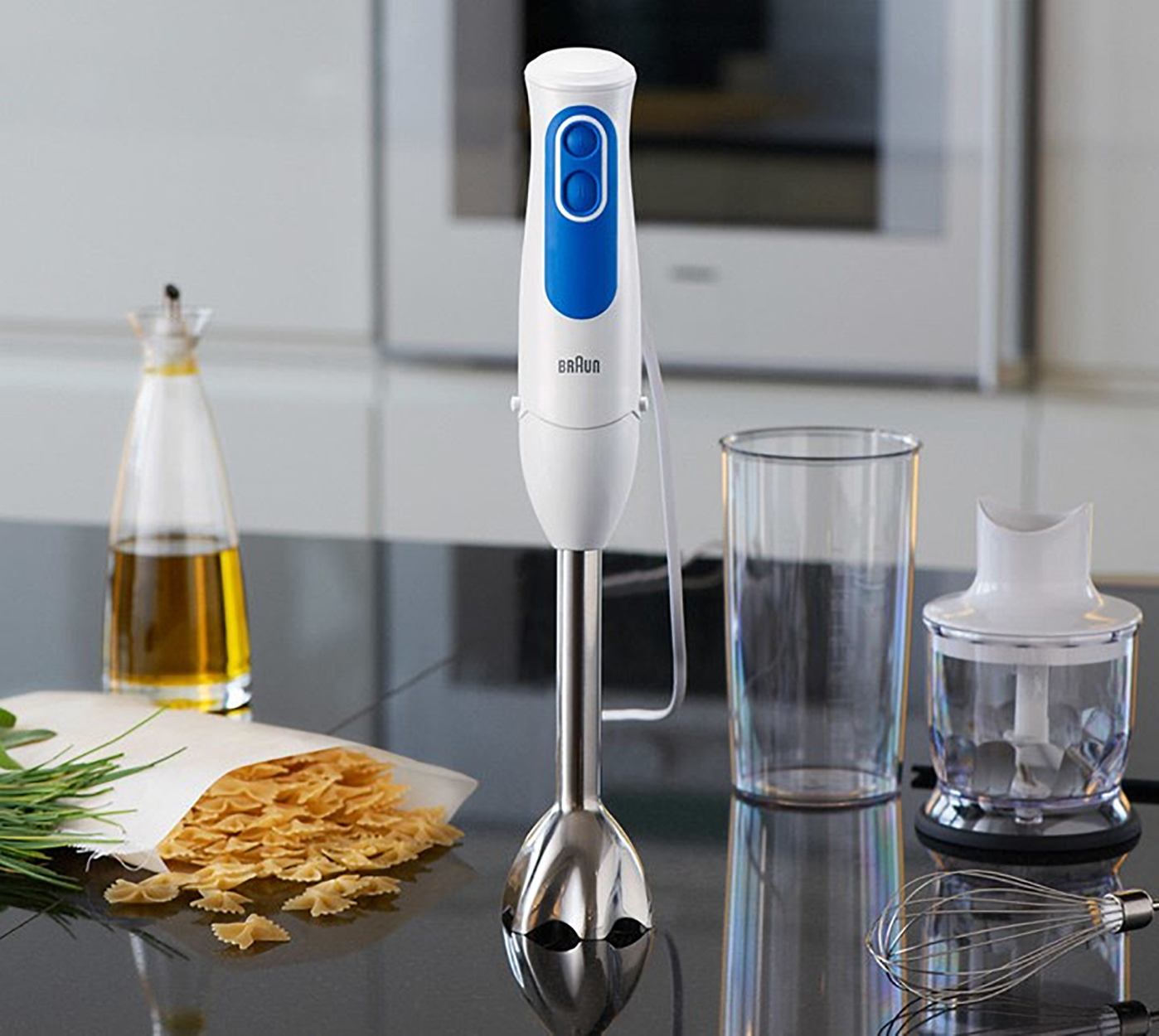 Ein Braun-Handmixer, weiß mit blauem Knopf. Zutaten: Pasta, Öl und Kräuter.
