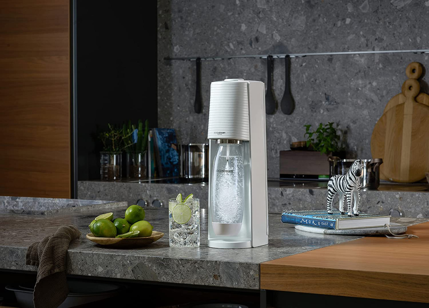 Eine weiße SodaStream-Maschine, ein Glas mit Eis und Limette, eine Zebrastatue.