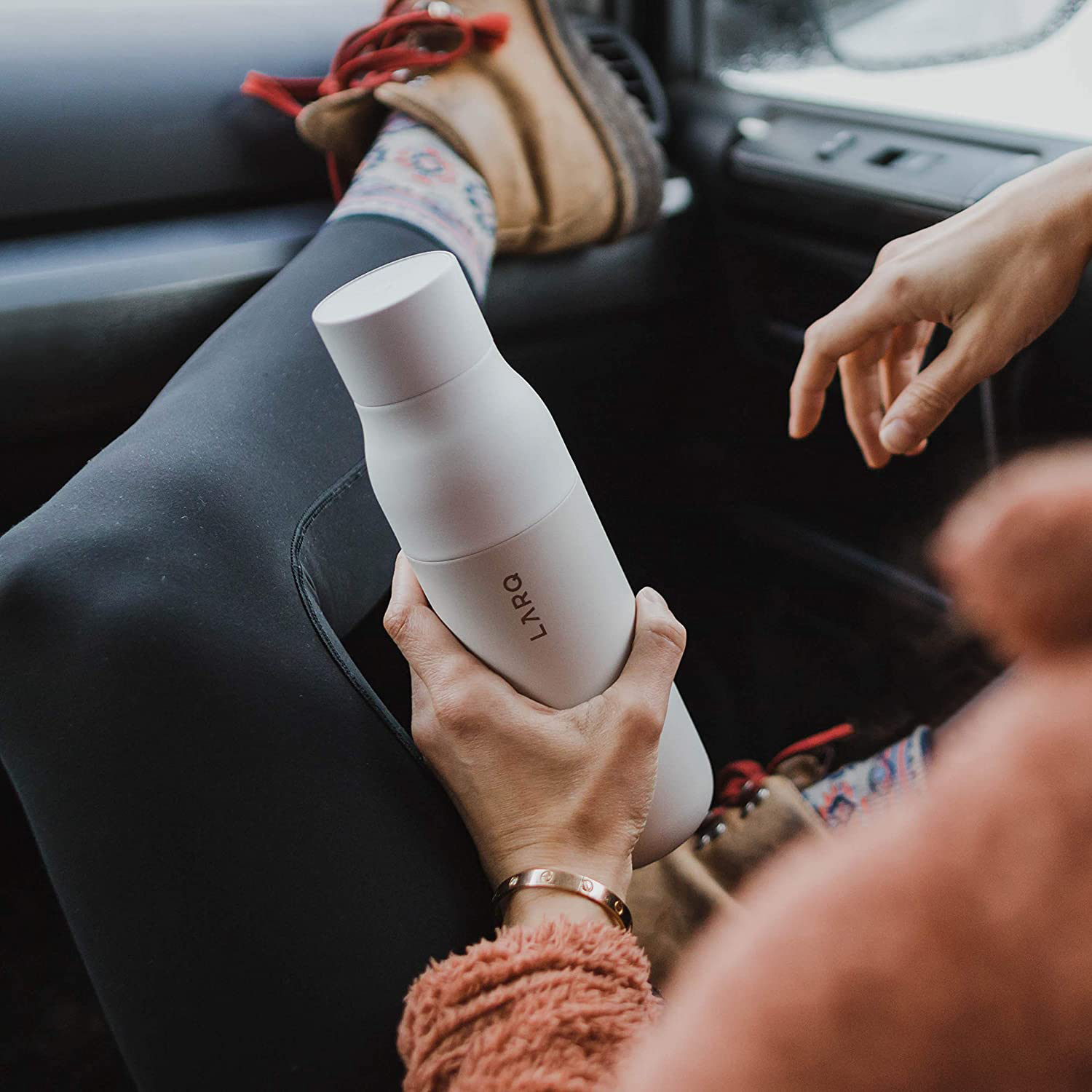 Person hält eine weiße Wasserflasche in einem Auto.