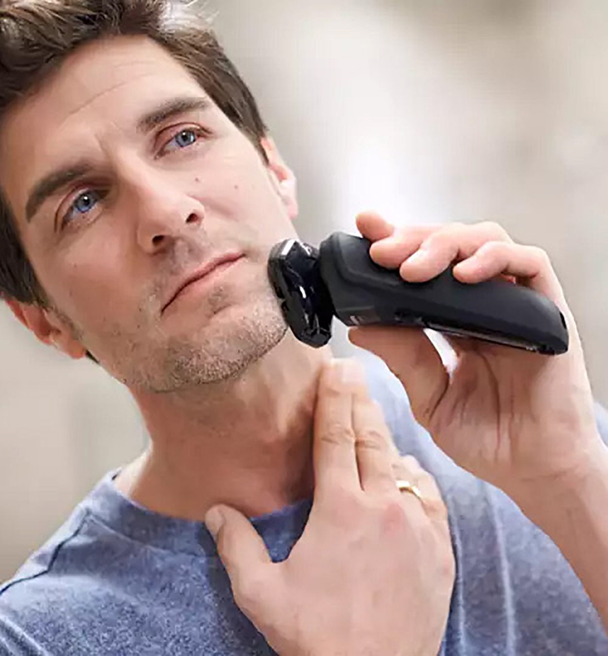 Un uomo si rade il collo con un rasoio elettrico.
