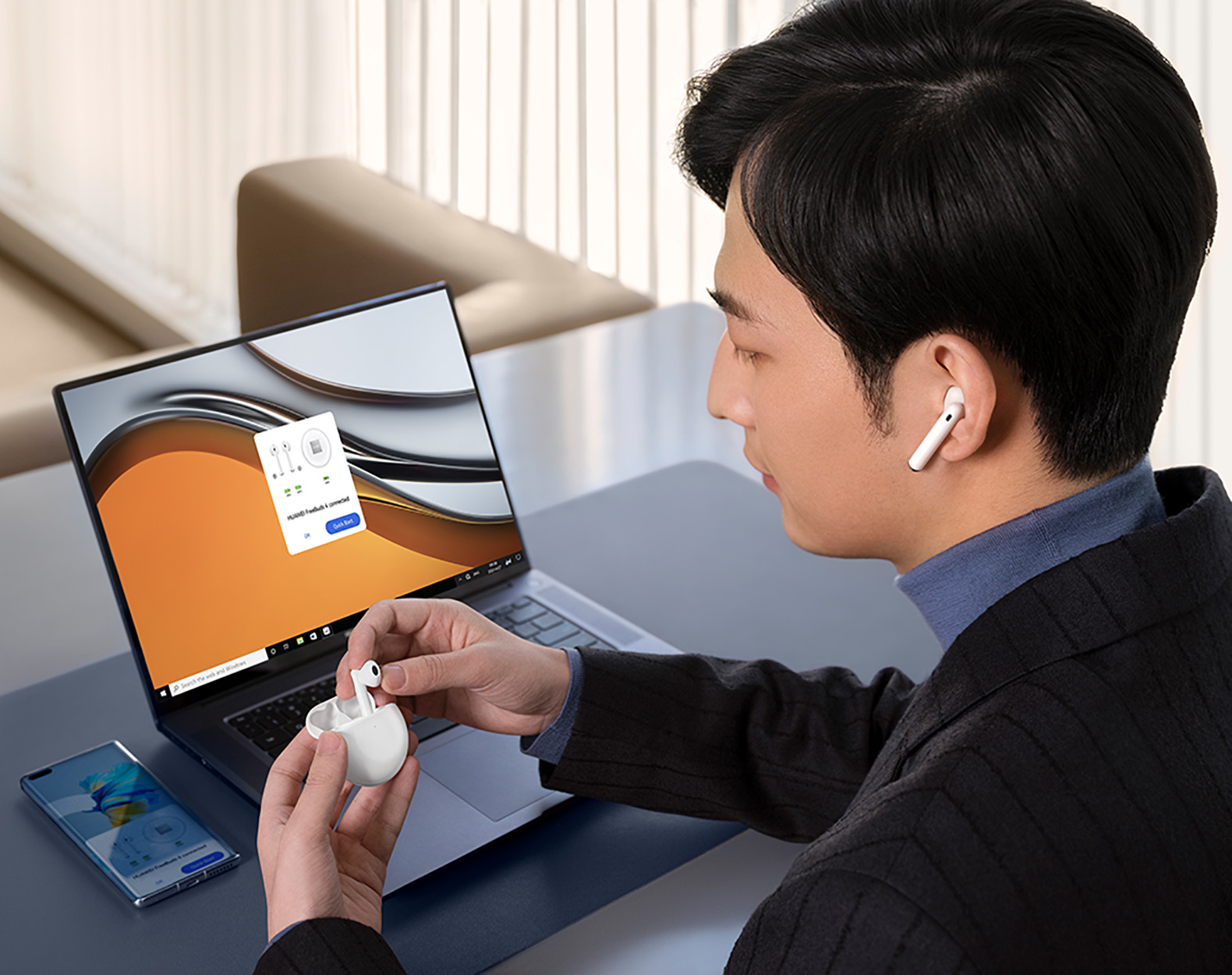 Mężczyzna w słuchawkach trzyma parę słuchawek w pobliżu laptopa.