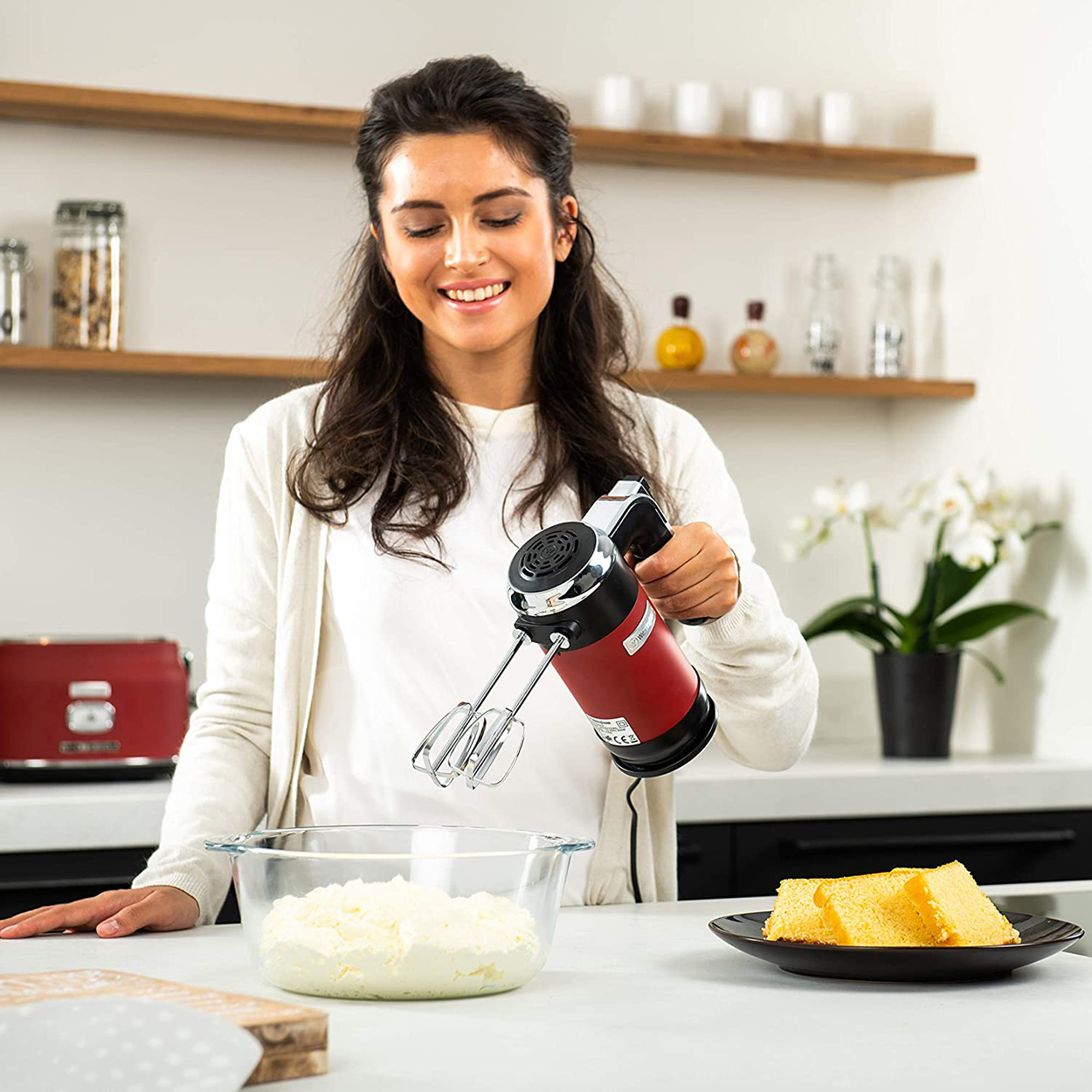 Eine Frau verwendet einen roten Handmixer, um Zutaten zu verrühren.