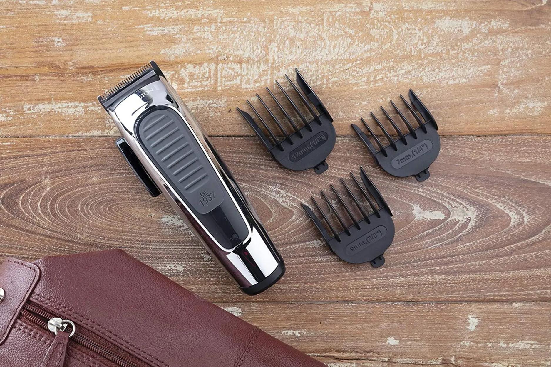 Cortapelos, cuchillas negras y guías de tamaño con bolsa de cuero sobre madera.