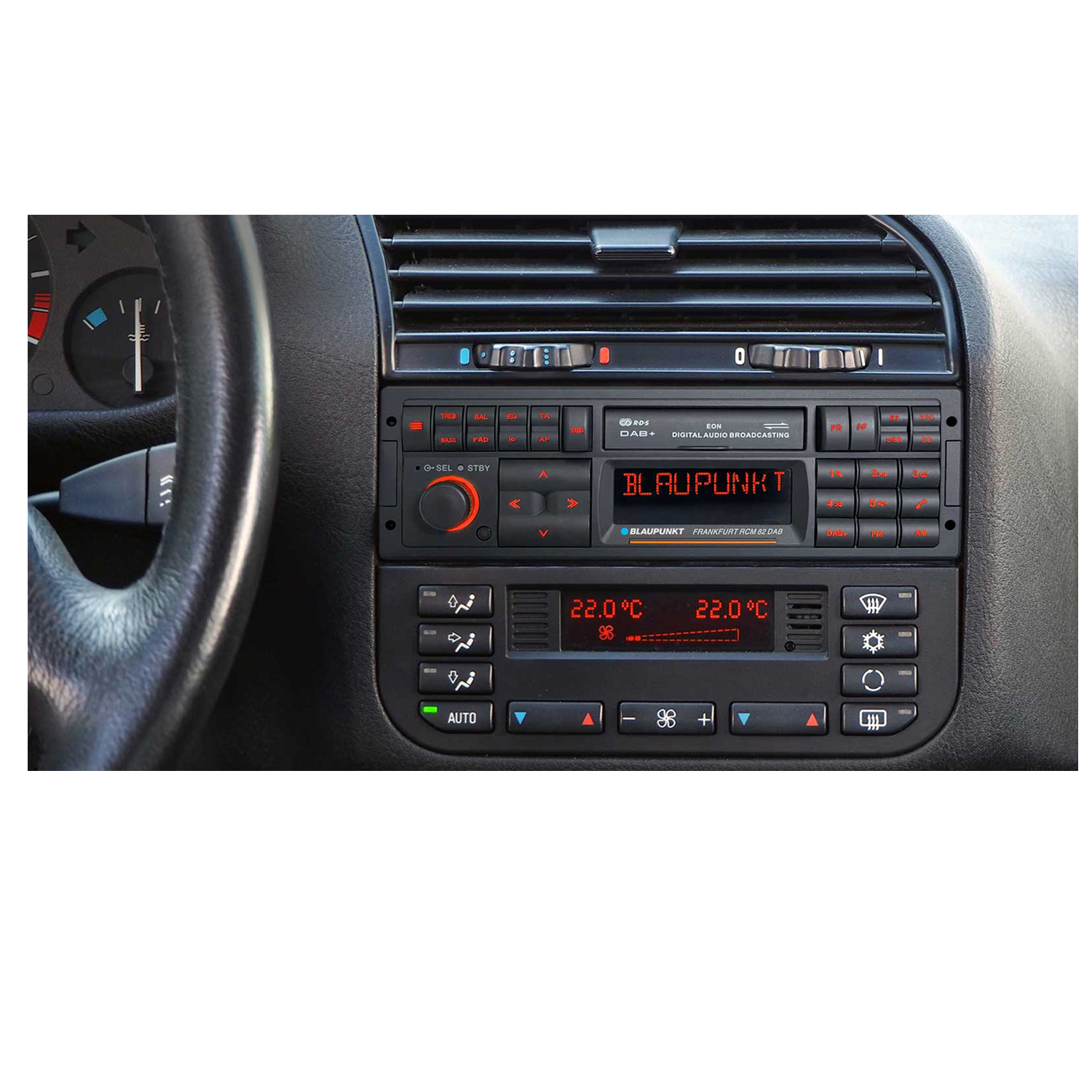 Autoradio avec écran rouge et divers boutons, avec une vue partielle du tableau de bord de la voiture.
