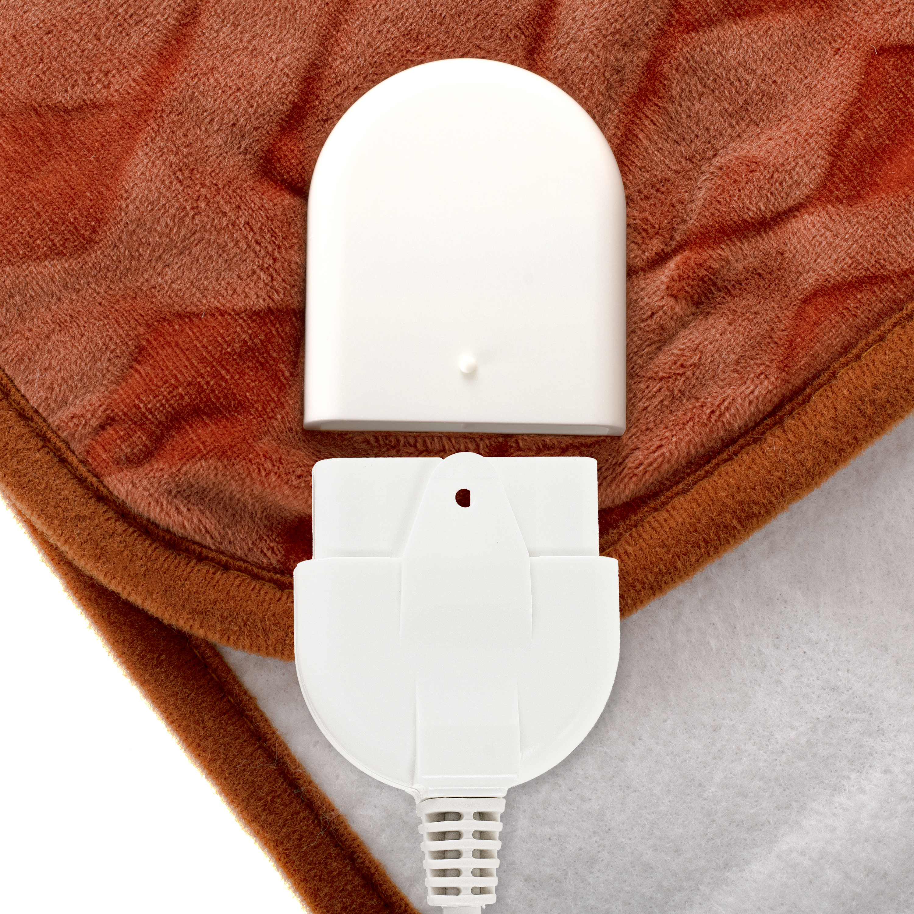 Eine braune Heizdecke mit weißem Netzteil, zeigt den Stecker und die Textur der Decke.