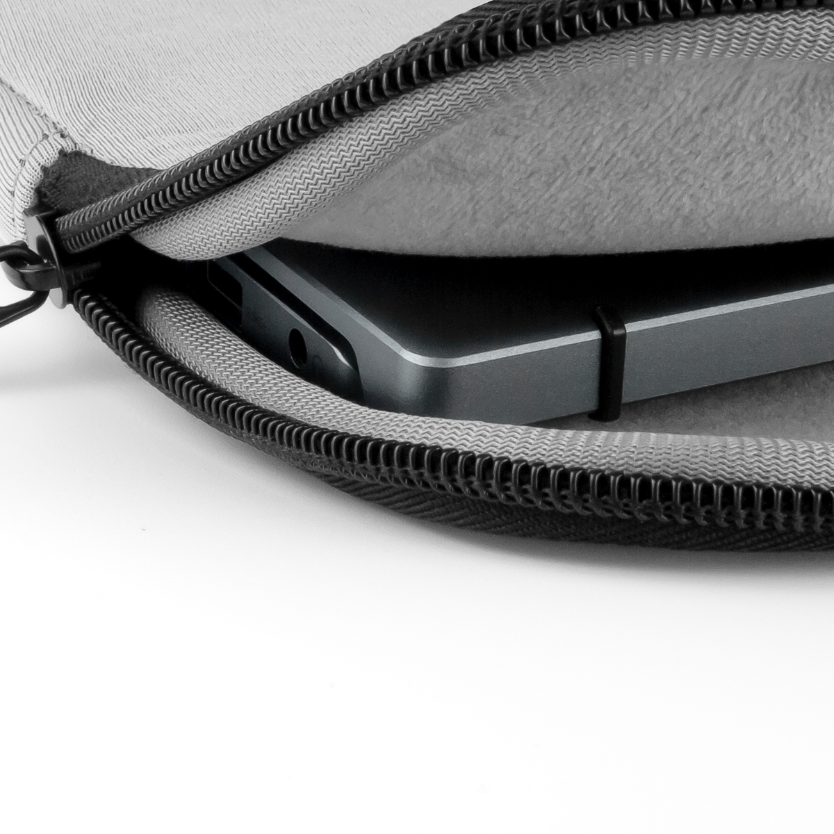 Una computadora portátil está en un estuche gris. El estuche está abierto, mostrando el interior y una cremallera negra.