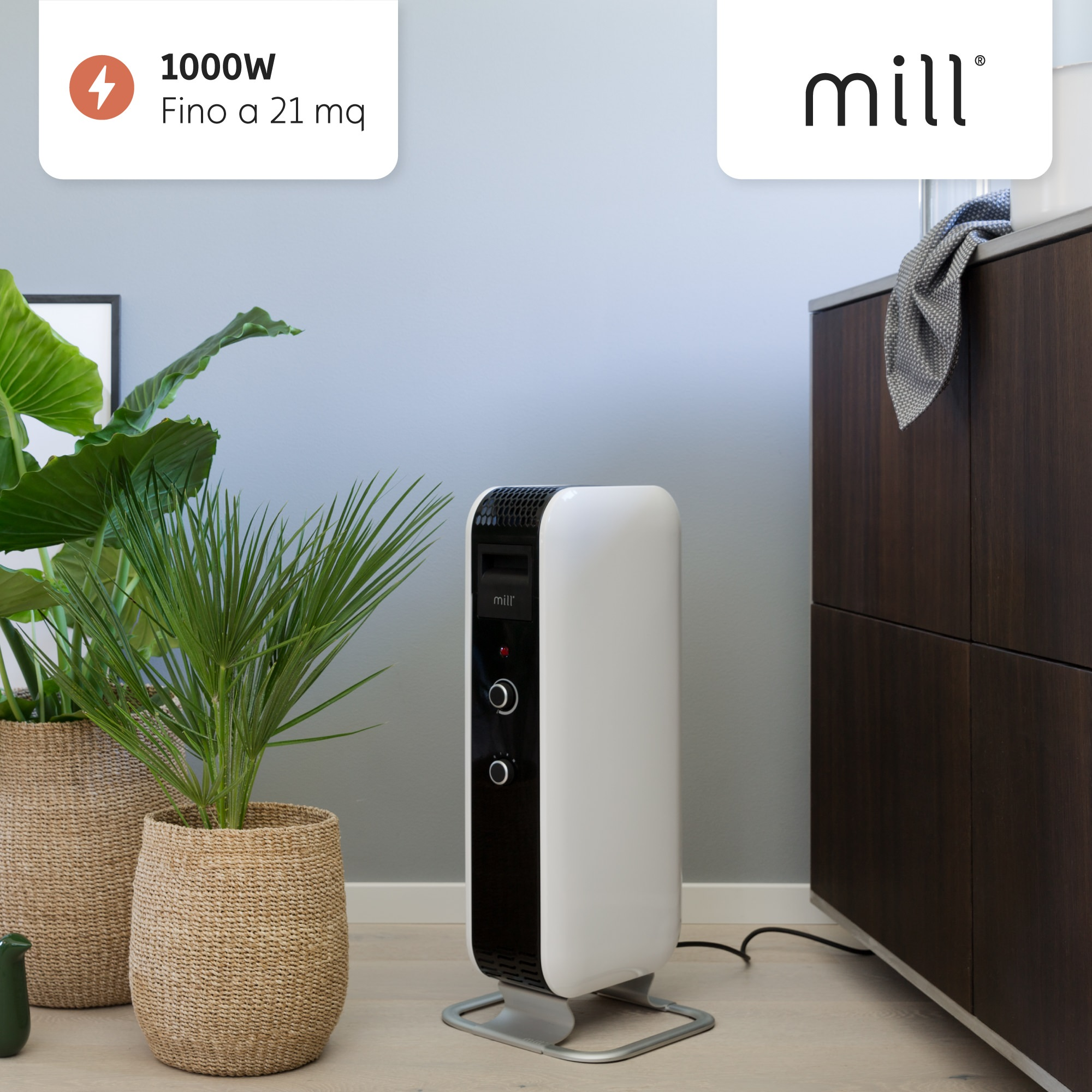 Wit en zwarte elektrische kachel met een plant aan weerszijden, in een kamer met grijze muren.