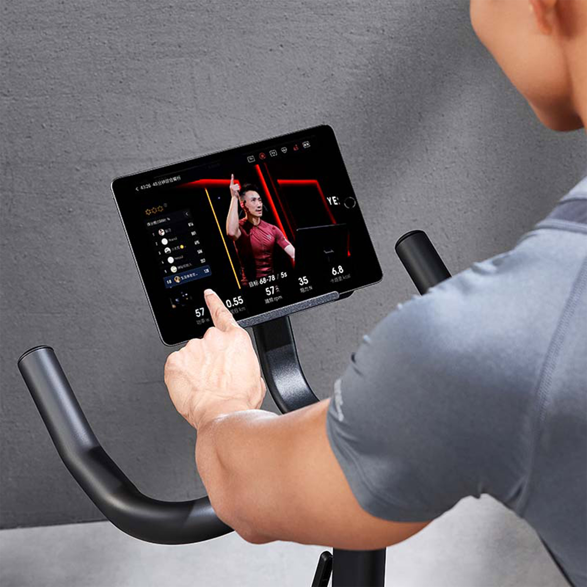 Una persona usa un tablet su una cyclette. Il tablet mostra un video di una persona che va in bicicletta.