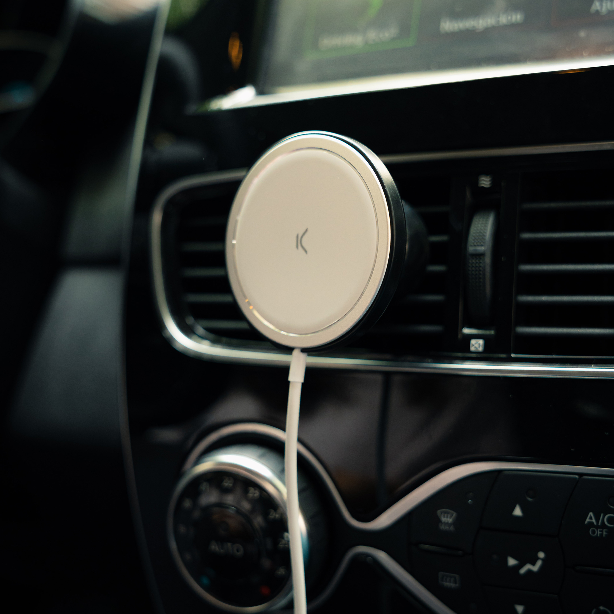 Una rejilla de ventilación de coche con un cargador de teléfono redondo blanco enchufado.
