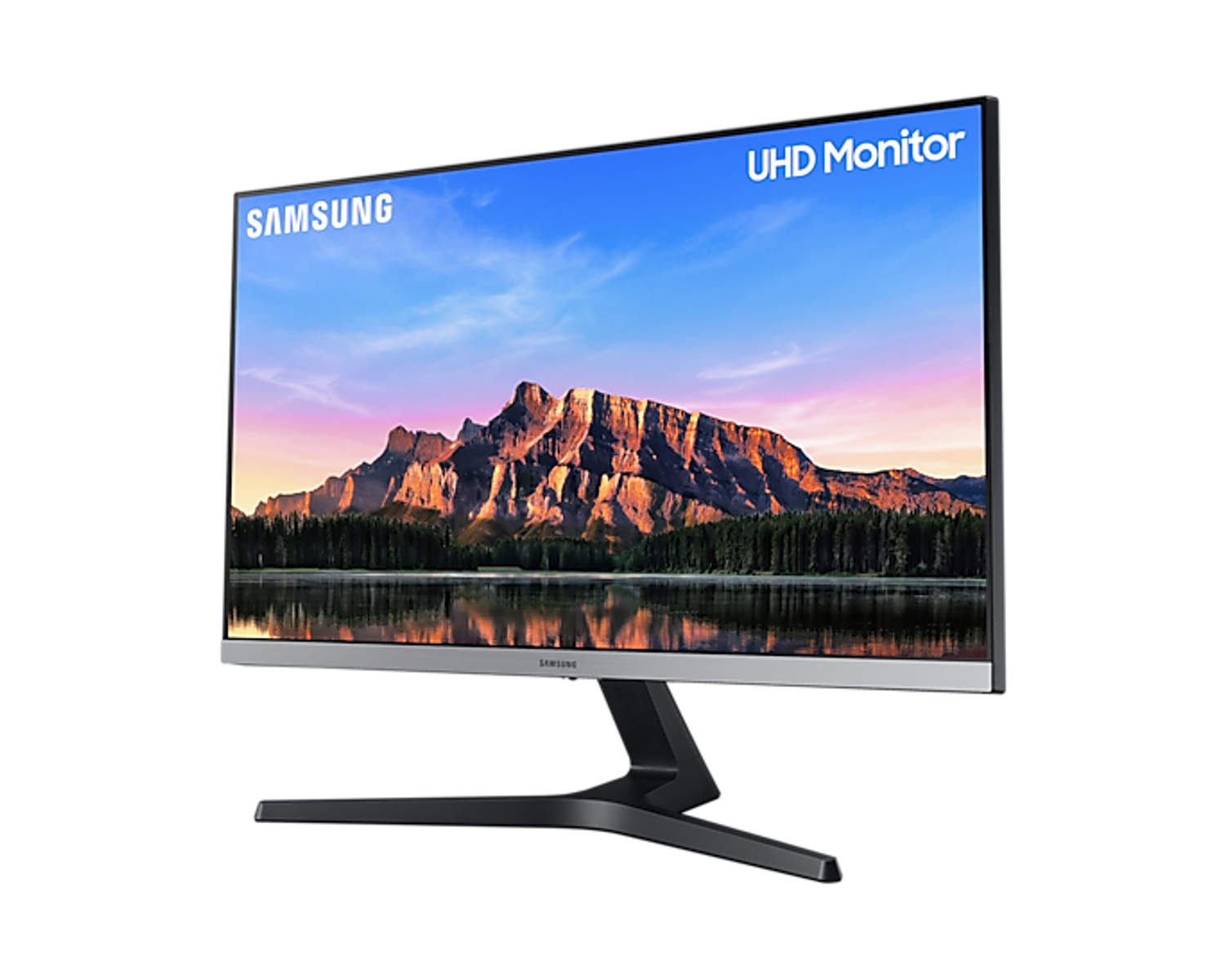 Un monitor Samsung mostra una scena paesaggistica con un lago e una catena montuosa sotto un cielo nuvoloso.