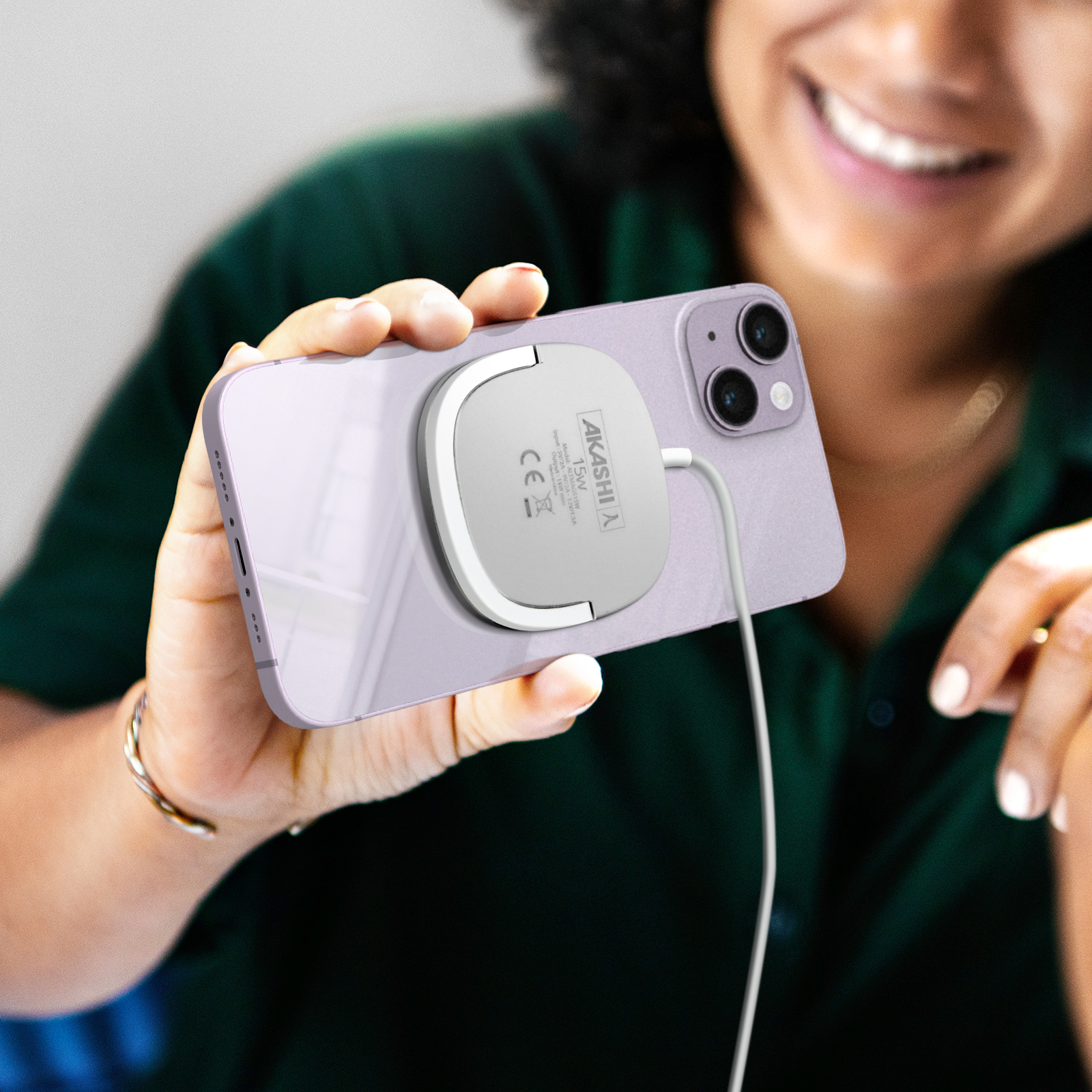 Una donna tiene un iPhone viola con caricatore magnetico bianco.