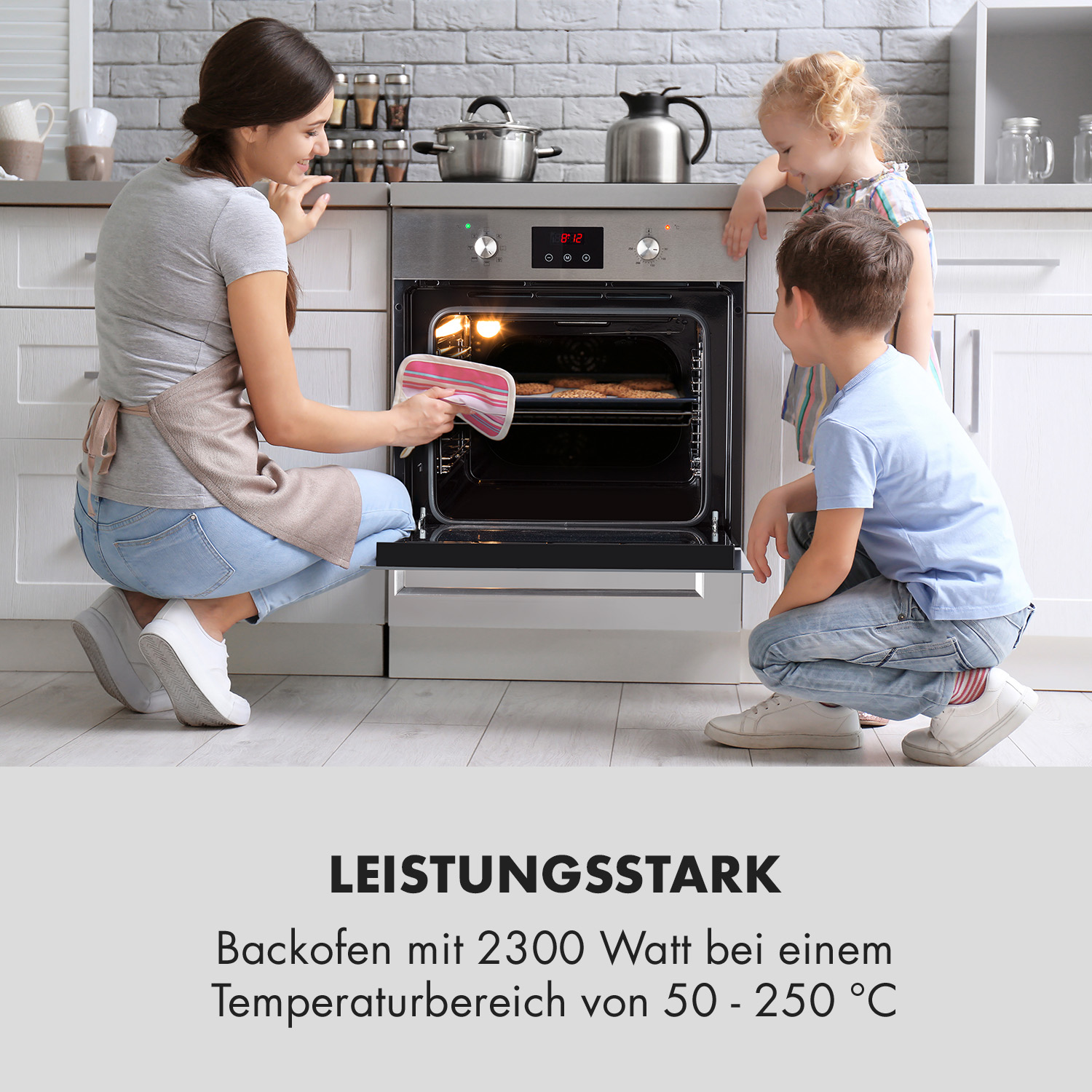 Eine Frau und zwei Kinder schauen in einen Ofen. Der Ofen ist offen, eine Frau hält einen Topflappen.