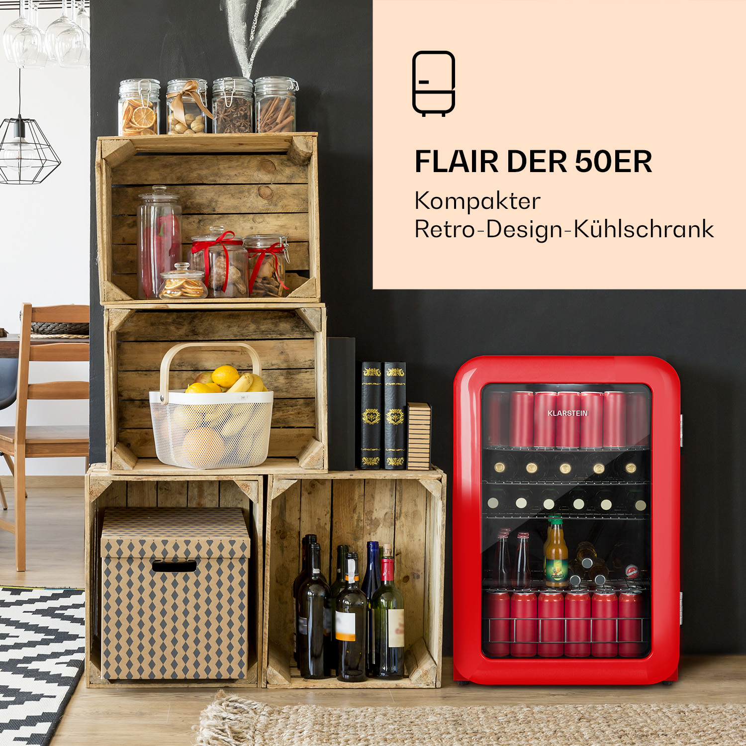 Un mini-frigorífico rojo de diseño retro junto a cajas de madera. Las cajas contienen artículos como tarros, botellas y una cesta.