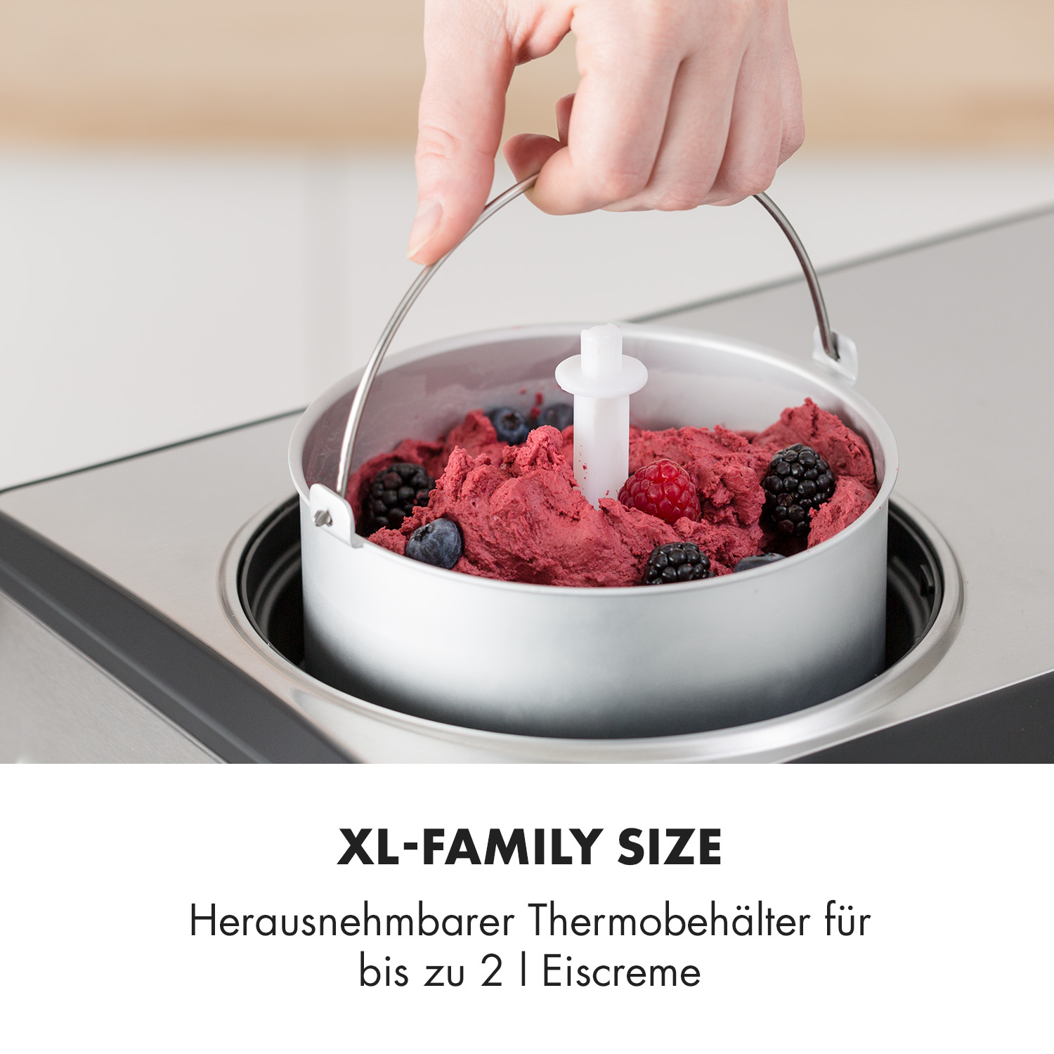 Eismaschine mit rotem Eis und Beeren im Metallbehälter.