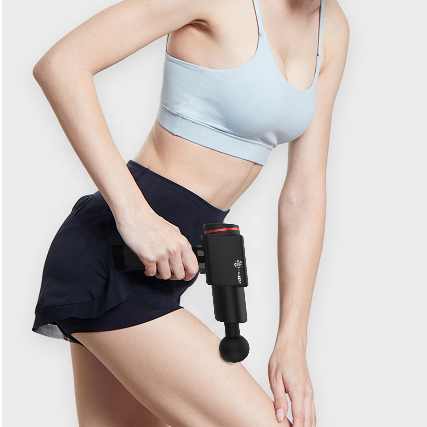 Frau in Sportkleidung, die eine schwarze Massagepistole auf ihrem Oberschenkel verwendet. Die Pistole ist schwarz.