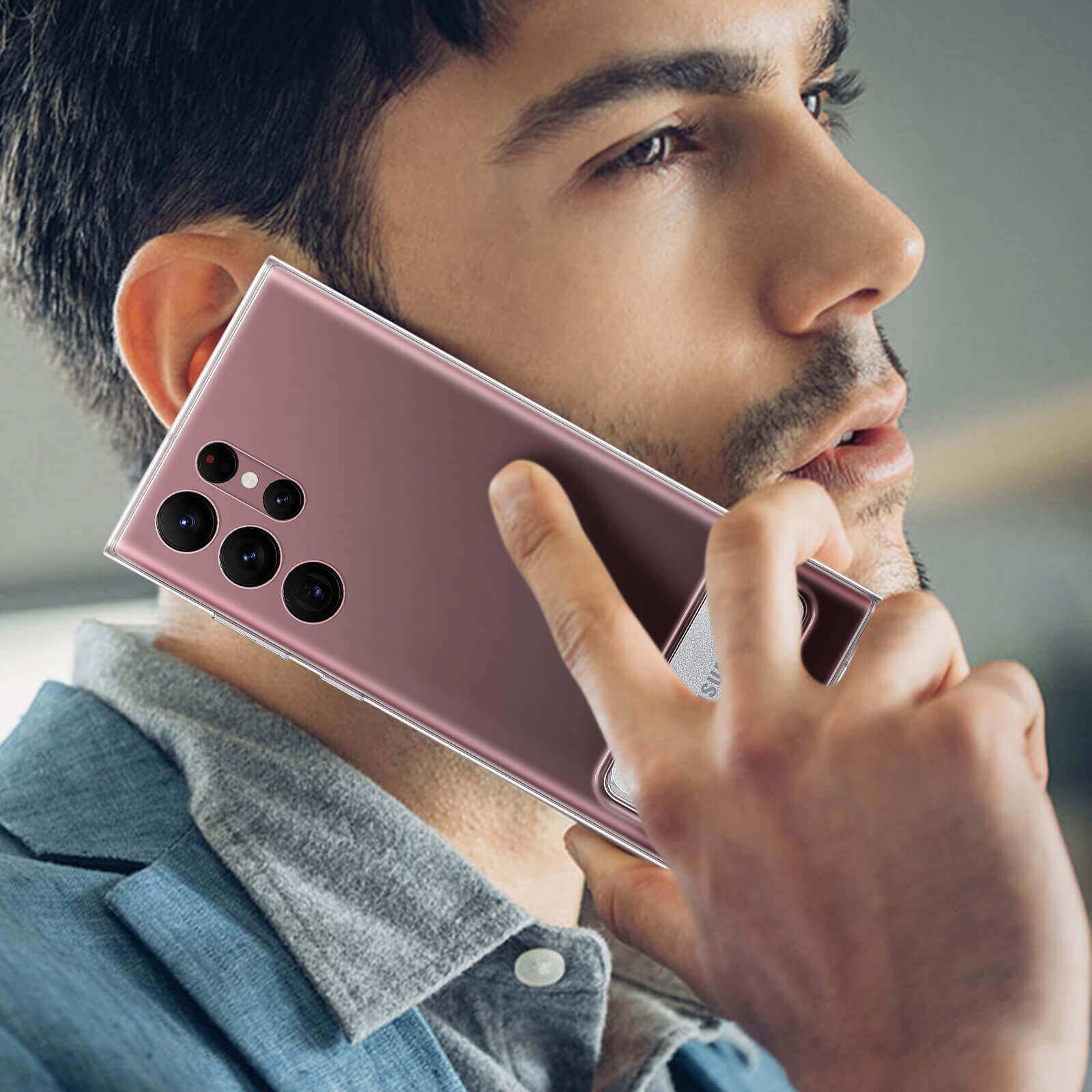 Un uomo che tiene una custodia rosa per telefono sul suo viso. Il telefono ha più obiettivi della fotocamera.