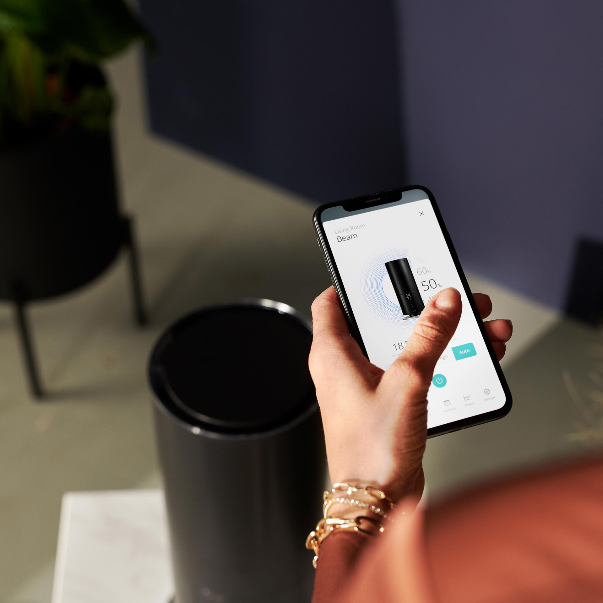 Dłoń trzymająca smartfon z interfejsem kontroli urządzenia smart home.