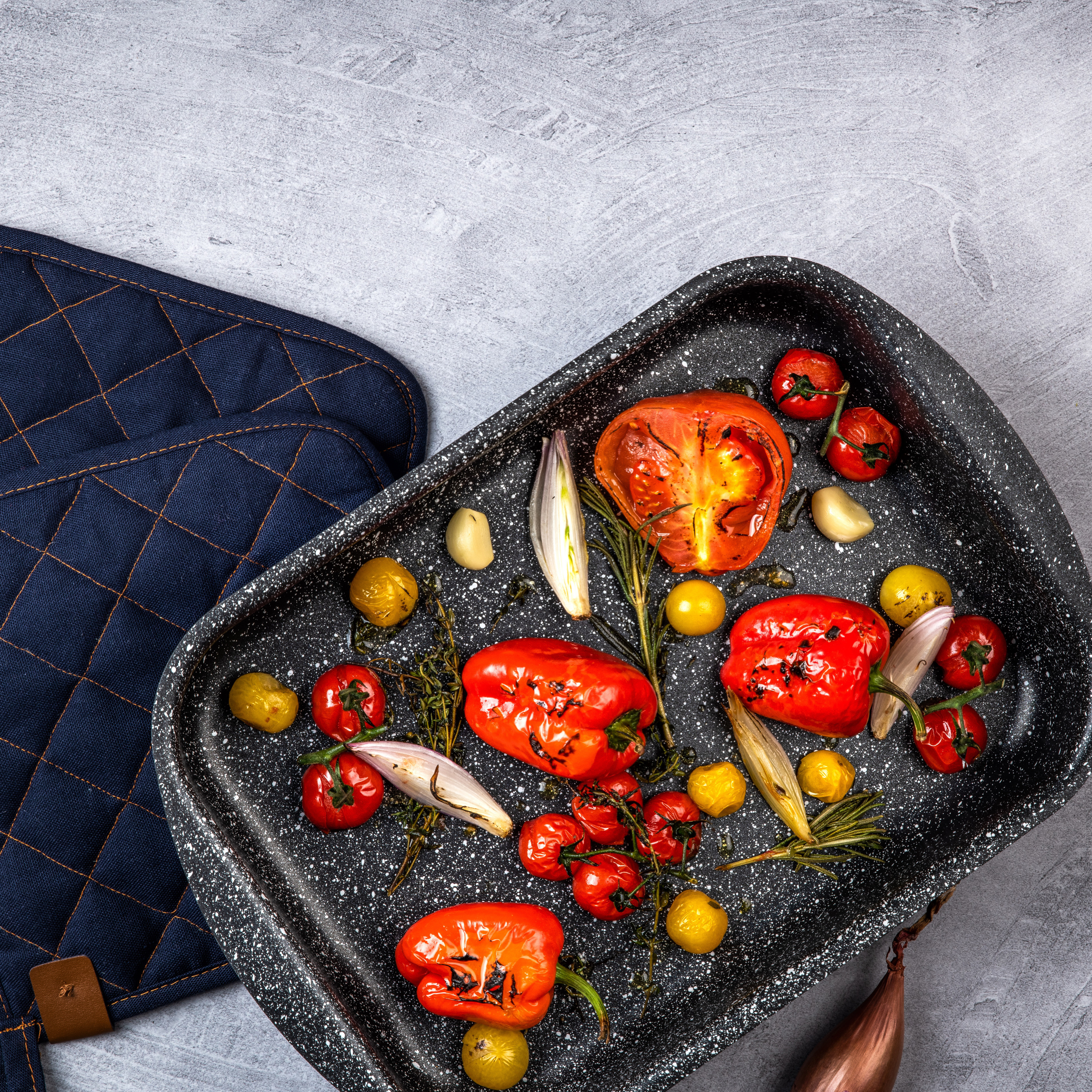 Geröstetes Gemüse in einer Schale. Tomaten, Paprika, Zwiebeln und Kräuter.