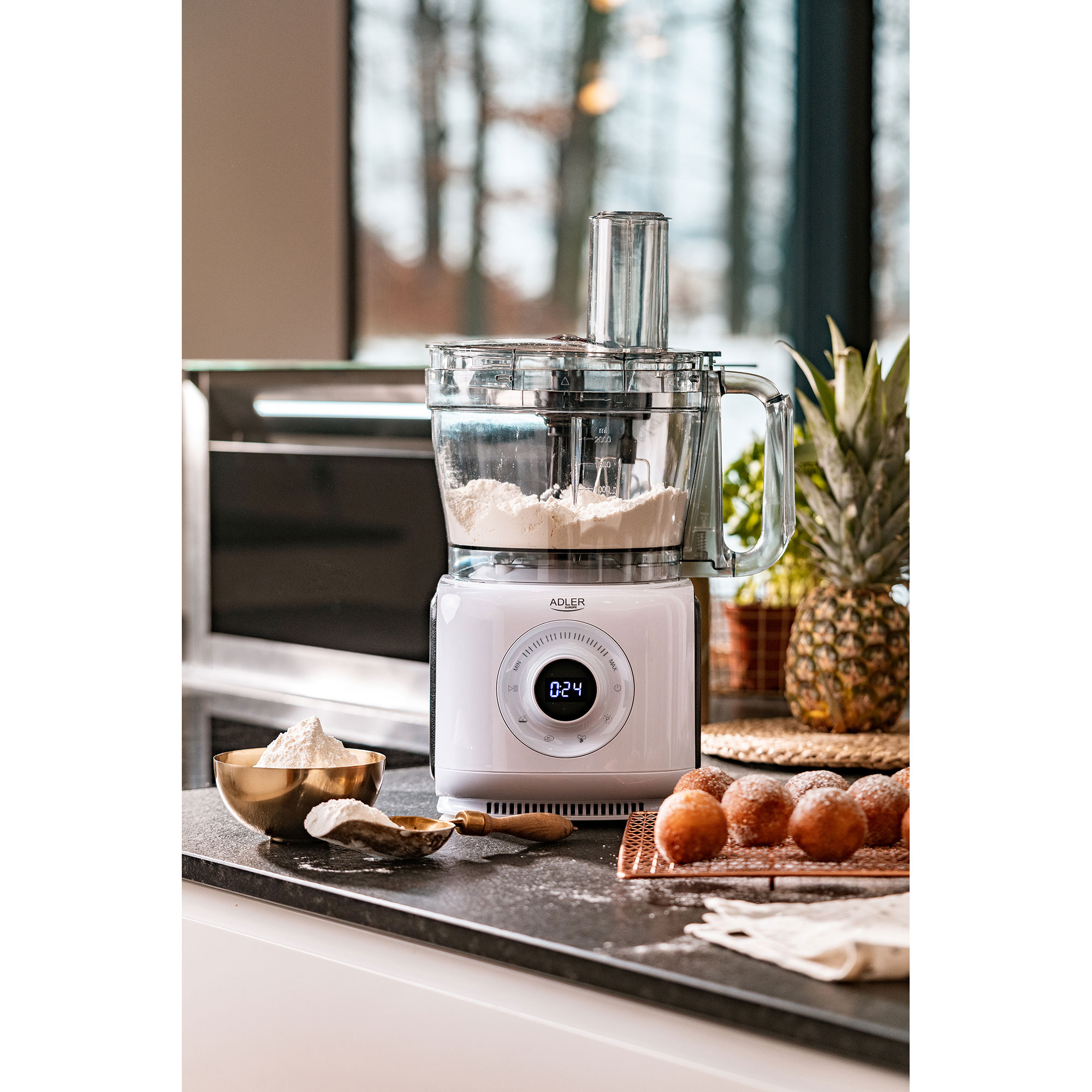 Robot da cucina bianco con ingredienti e ananas. Farina in una ciotola e pasticcini a forma di donut. Interno.
